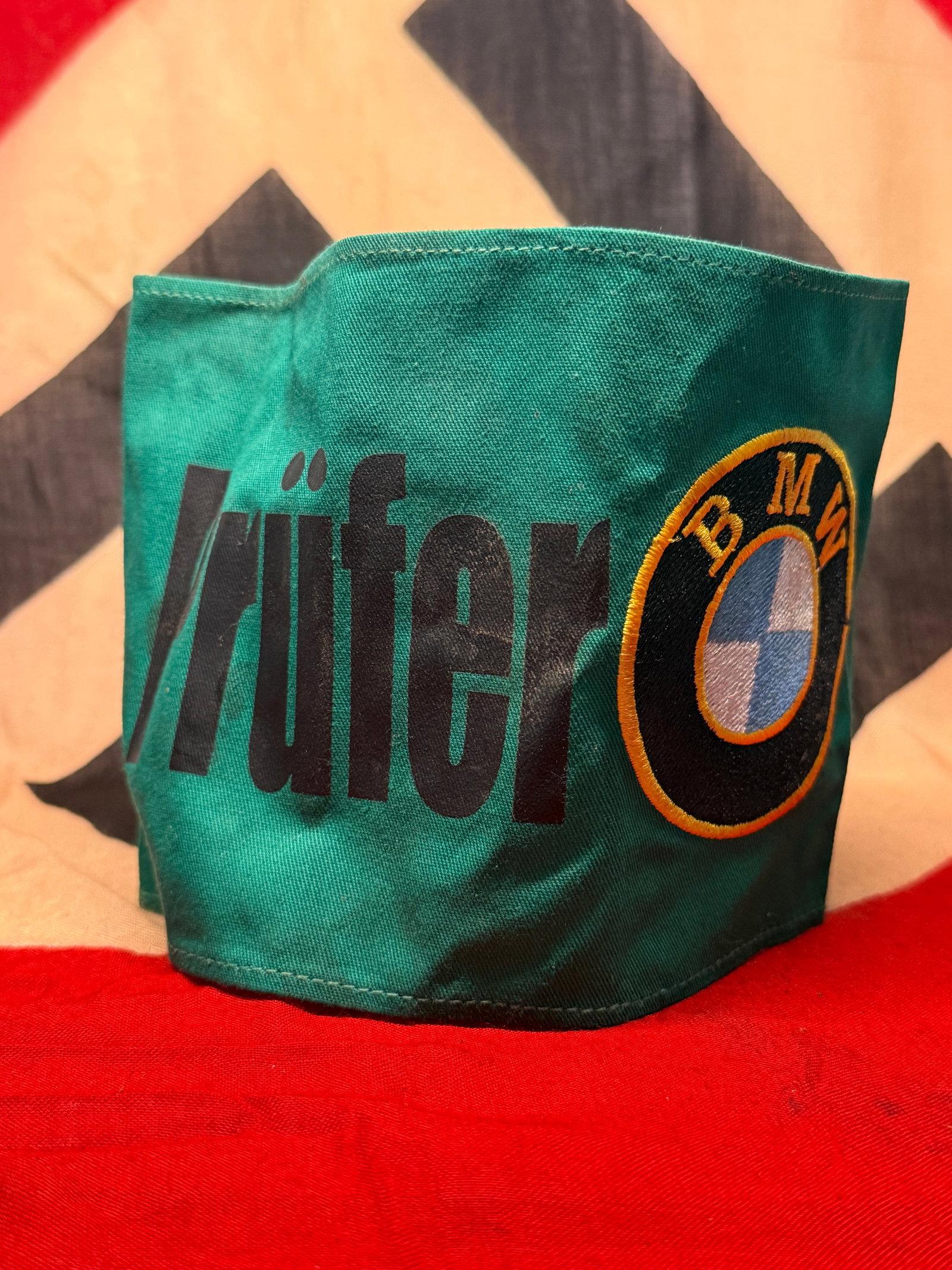 WWII German BMW “Prüfer?? Factory Inspector Armband with RZM Label No. 722: A distinctive green cloth armband prominently printed with the German word “Prüfer,” meaning “inspector” or “examiner,” accompanied by an embroidered circular BMW emblem in bl