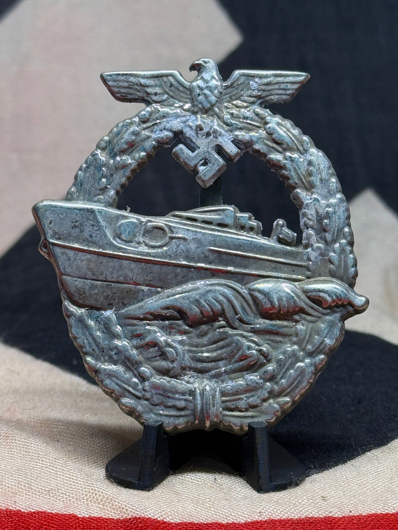 WWII German Kriegsmarine E-Boat War Badge – Schwerin Berlin Marked: This WWII German naval badge displays the unmistakable Schnellboot, or fast attack craft, motif associated with the Kriegsmarine E-Boat War Badge. The obverse depicts a high-speed naval craft cutting 