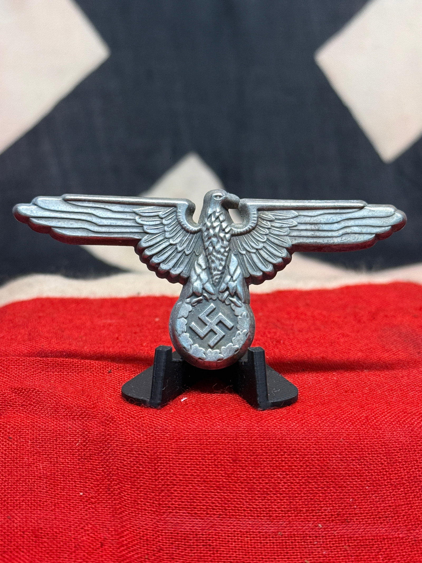 WWII German SS Mützenadler Visor Cap Eagle Insignia: A large silver-colored German SS Mützenadler, or visor-cap eagle insignia, displaying the distinctive horizontally extended wings associated with SS peaked-cap insignia. The eagle is rendered with sh