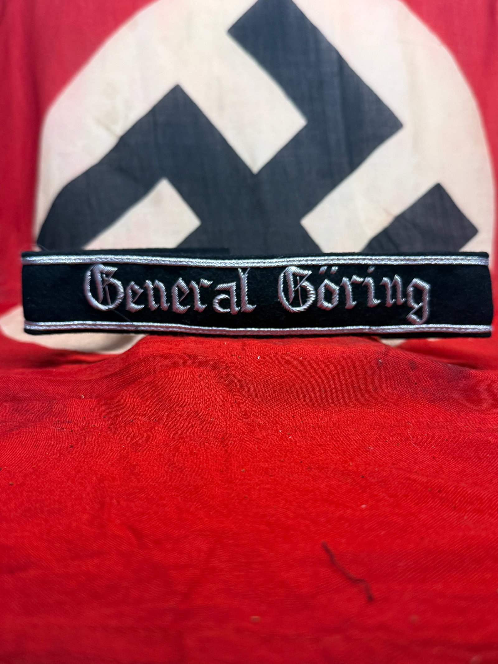 WWII German “General Göring?? Cuff Title with Silver Embroidered Gothic Lettering: This black cloth cuff title features the prominent inscription “General Göring” executed in silver-gray Gothic-style embroidery and framed along the upper and lower edges by narrow silver-col