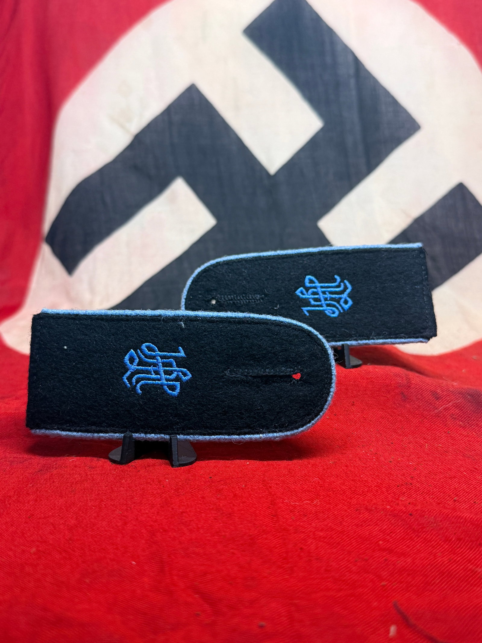 WWII German Military Medical Service Shoulder Boards with Blue Caduceus Insignia – Pair: A matching pair of black wool shoulder boards distinguished by contrasting blue edging and prominently embroidered blue medical caduceus-style devices on their faces. Each board is constructed in the 