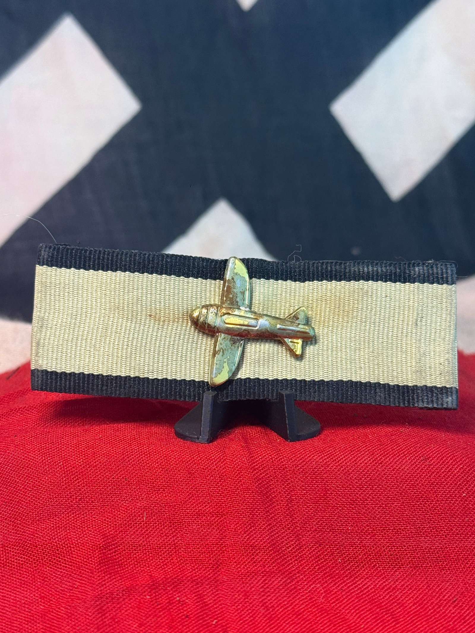 WWII German Low-Flying Aircraft Destruction Badge with Metal Aircraft Device: This unusual WWII German military award consists of a three-dimensional metal aircraft device mounted horizontally across a rectangular woven cloth backing. The aircraft is depicted with a prominent e