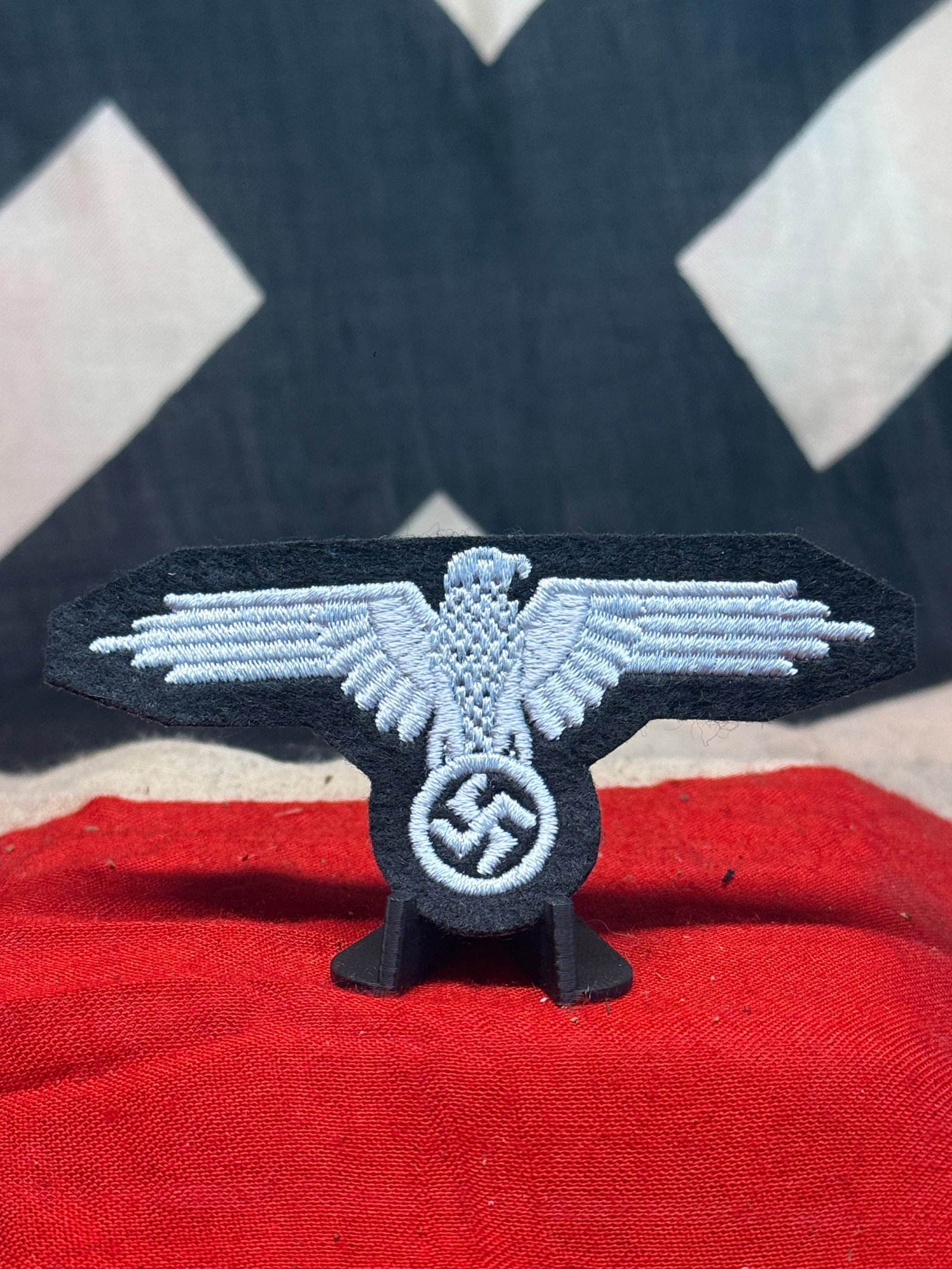 WWII German Heer BeVo-Style Breast Eagle Insignia – Silver-Gray on Black: This WWII German military cloth insignia features a spread-wing national eagle clutching a wreathed swastika, executed in tightly woven silver-gray thread against a shaped black textile backing. The e