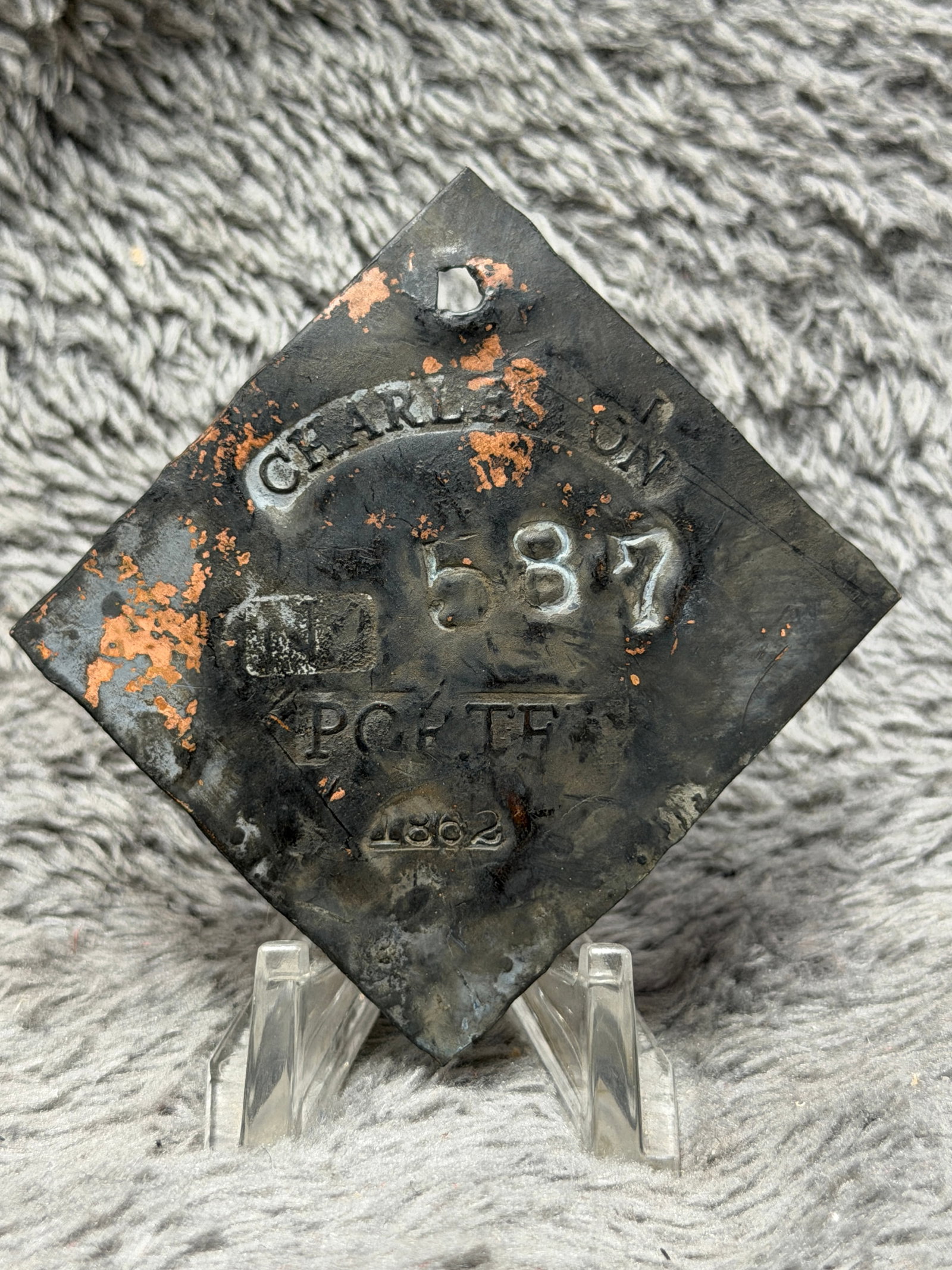 1862 Charleston No. 587 Porter Slave Hire Identification Tag: Civil War-era 1862 Charleston slave hire identification tag featuring a large diamond-shaped metal form with a pierced suspension hole at the upper point. The face is prominently stamped “CHARLESTON