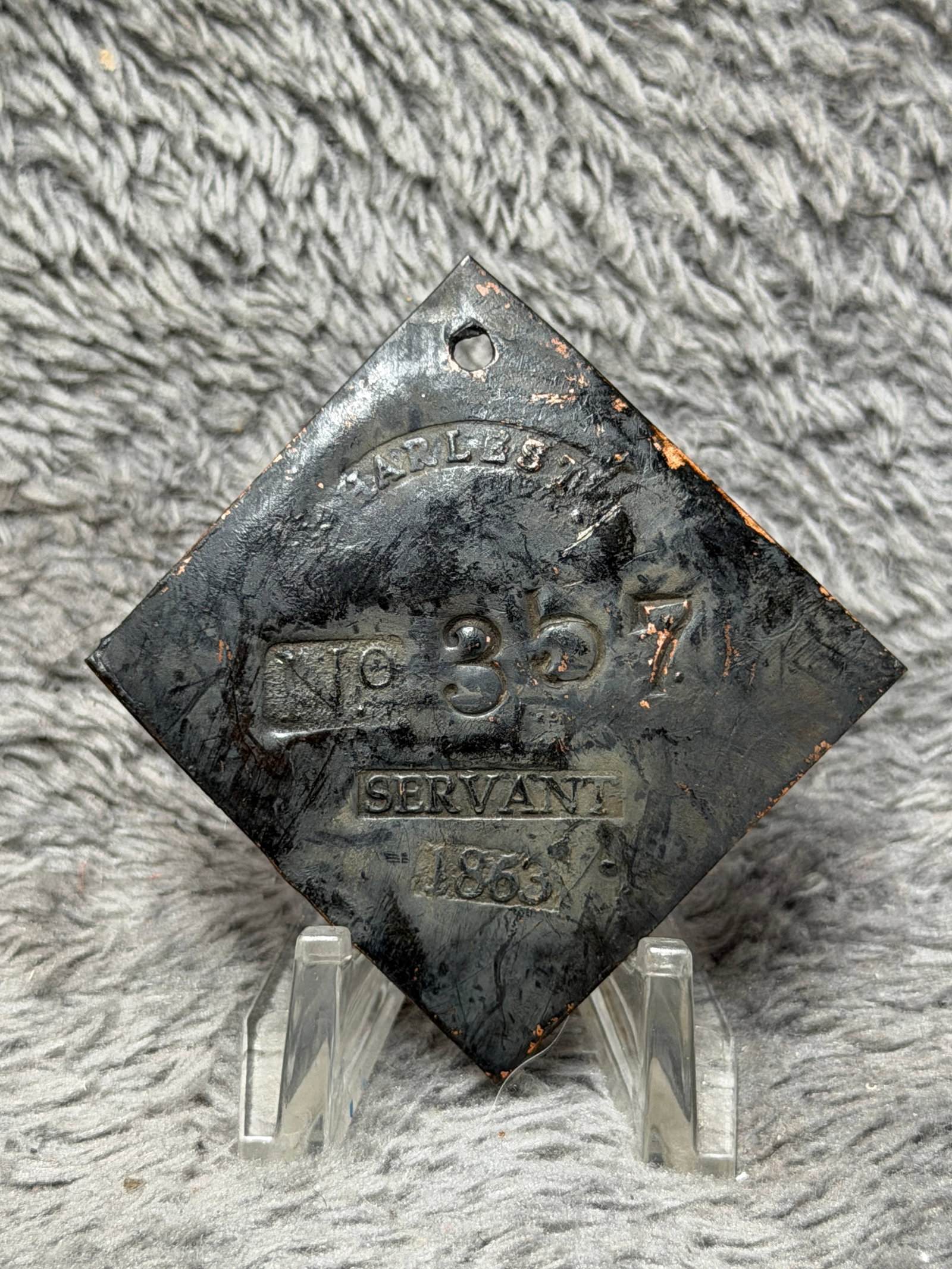 1863 Charleston No. 357 Servant Slave Hire Identification Tag: Pre-Civil War 1863 Charleston slave hire identification tag featuring a diamond-shaped metal form with a pierced suspension hole at the upper point. The face is prominently stamped “CHARLESTON&rdquo
