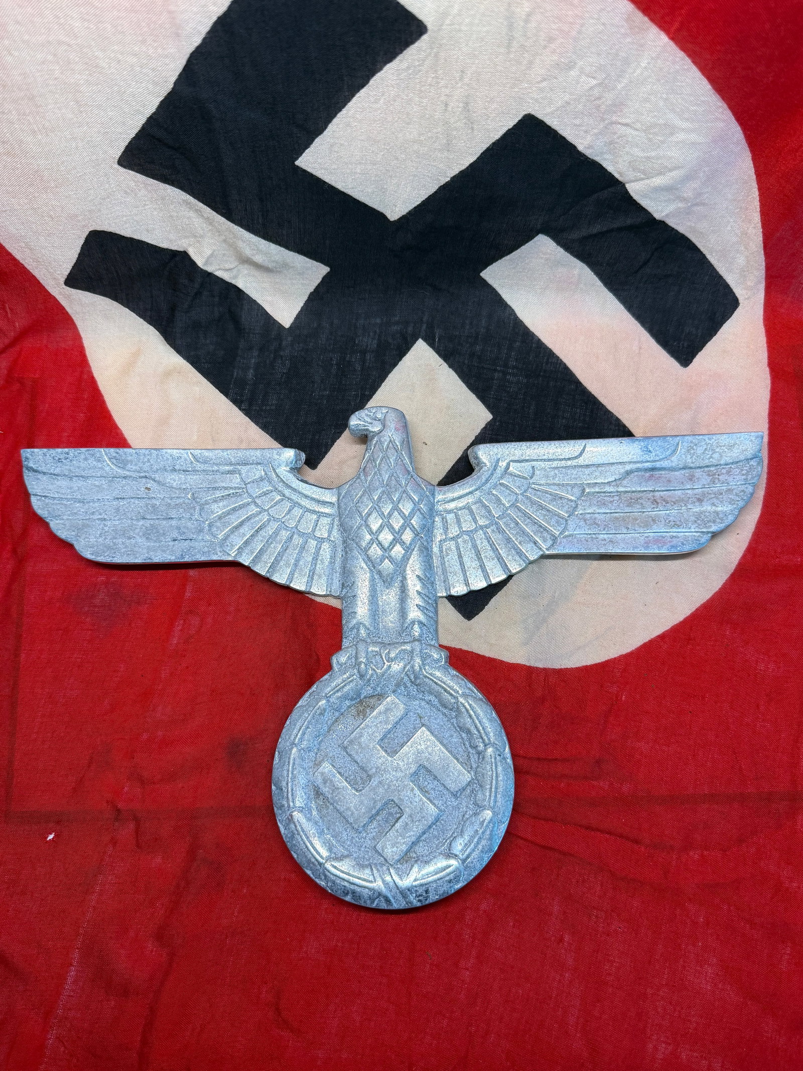WWII German NSDAP Large Metal Eagle & Swastika Wall or Building Emblem with RZM Label: A substantial silver-colored German political eagle emblem depicting a stylized eagle with fully extended wings above a large circular wreath enclosing a swastika. The sharply modeled front incorporat