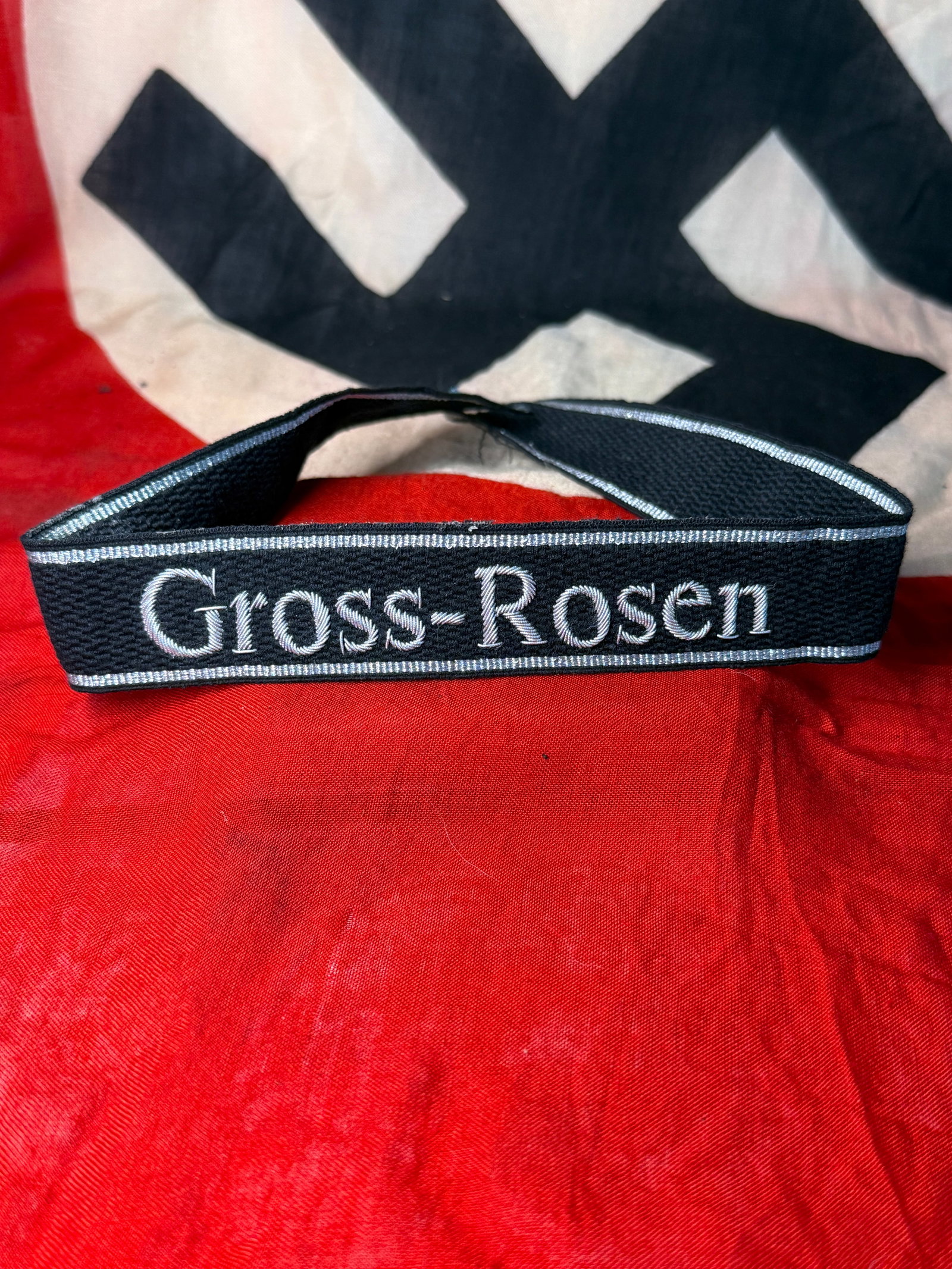 WWII German Waffen-SS “Gross-Rosen?? Concentration Camp Cuff Title: Black woven German cuff title embroidered with the name “Gross-Rosen” in silver-gray Gothic lettering and bordered along the upper and lower edges with matching silver-gray woven piping. The r