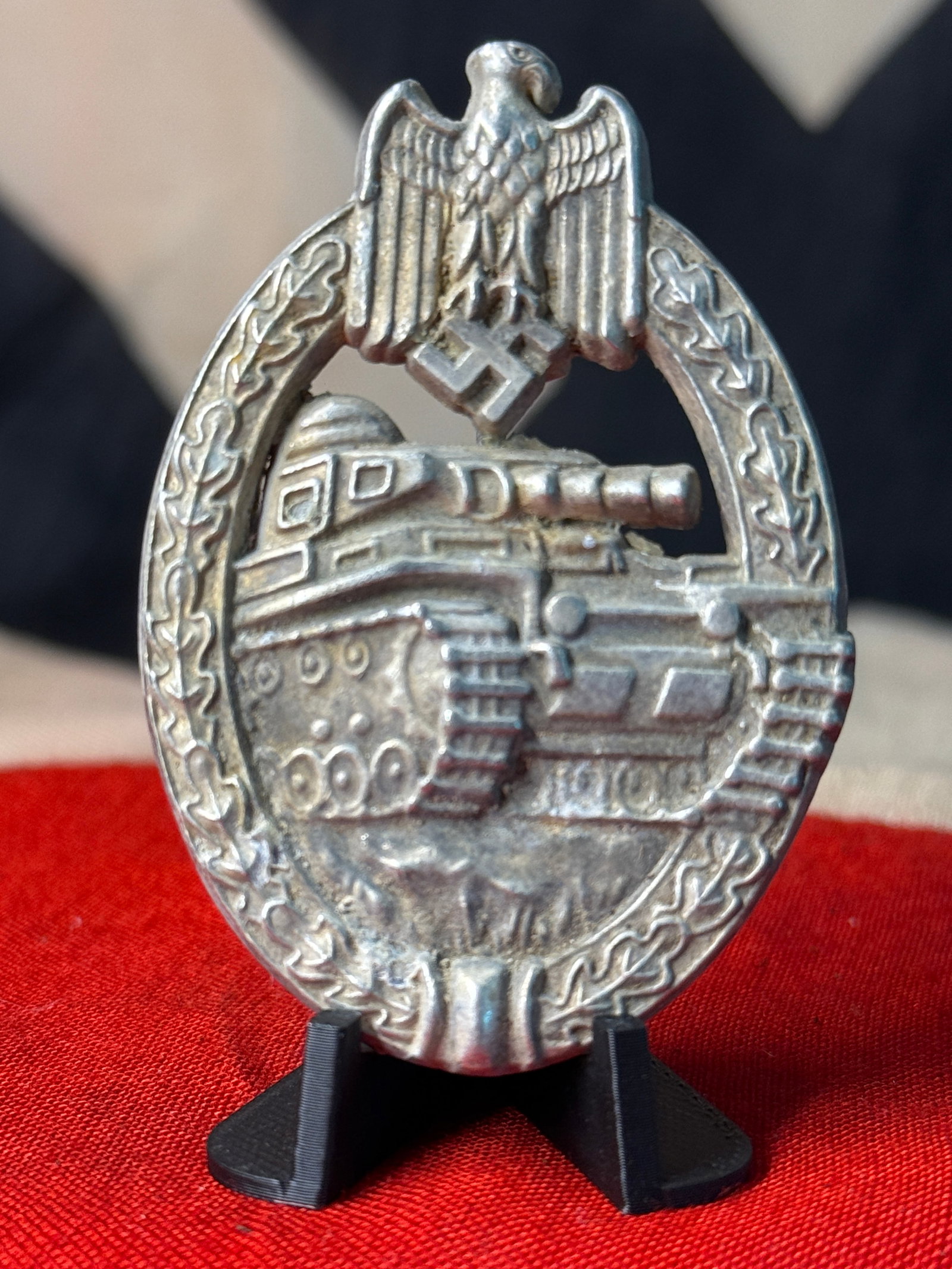 WWII German Army Heer Panzer Assault Badge – Silver Grade: Oval silver-colored German military combat badge dominated by a detailed frontal depiction of a tracked Panzer tank advancing across the lower field. The vehicle is enclosed by an oak-leaf wreath surm