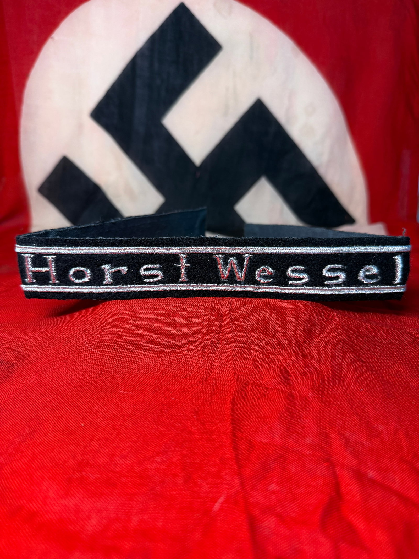 WWII German “Horst Wessel?? Silver-Embroidered Cuff Title: A black wool cuff title bearing the name “Horst Wessel” prominently embroidered in silver-gray Gothic-style lettering, bordered along the upper and lower edges by narrow silver-colored woven p