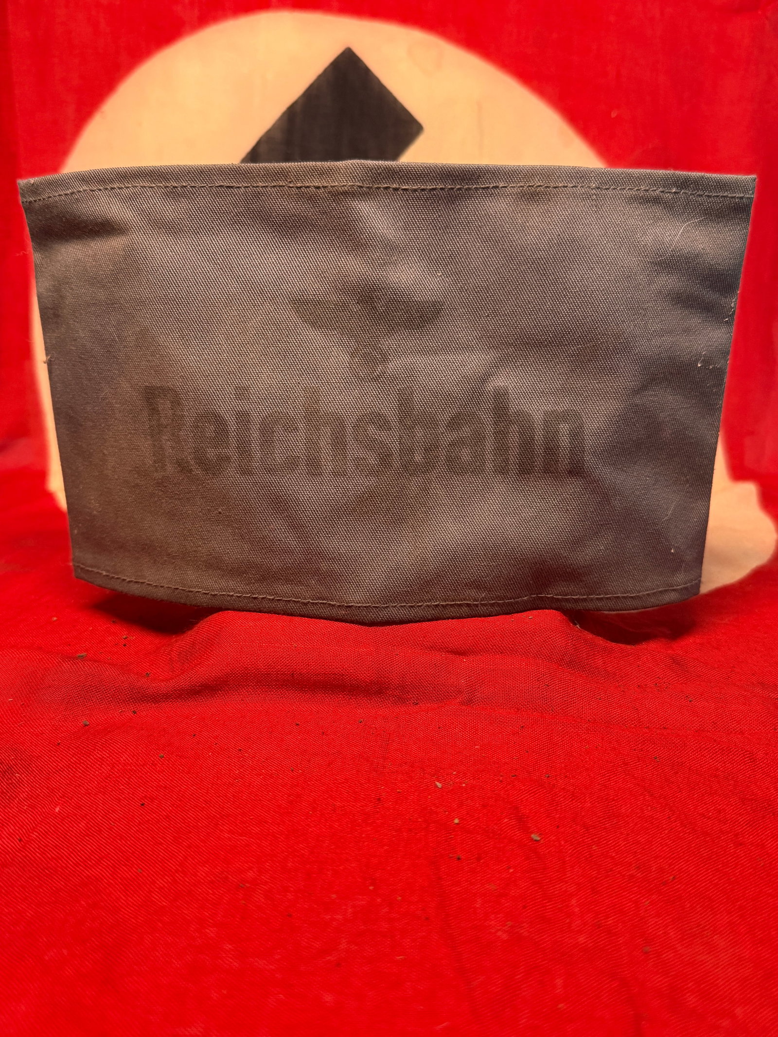 WWII German Reichsbahn RZM Marked Black Armband with Paper Tag: WWII German Reichsbahn black cloth armband featuring a subdued black construction with finished upper and lower edges and a machine-sewn rear joining seam. The exterior displays a faint “Reichsbahn&