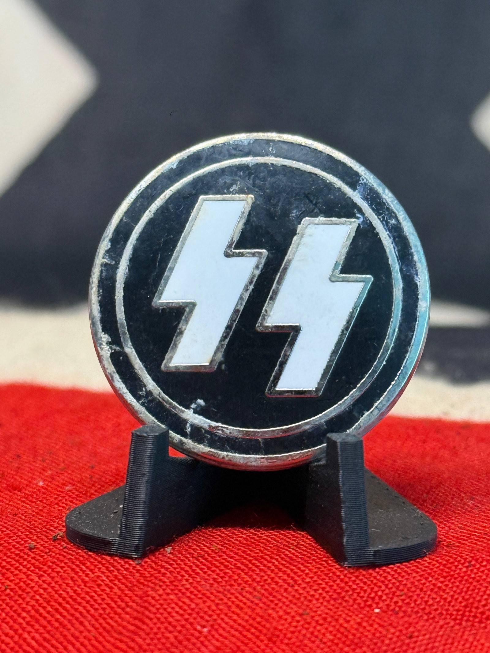 WWII German Waffen-SS Runes Enamel Membership Badge: A circular German SS insignia featuring the organization’s distinctive double Sig runes prominently displayed in white against a glossy black field. The runes are individually outlined by raised sil