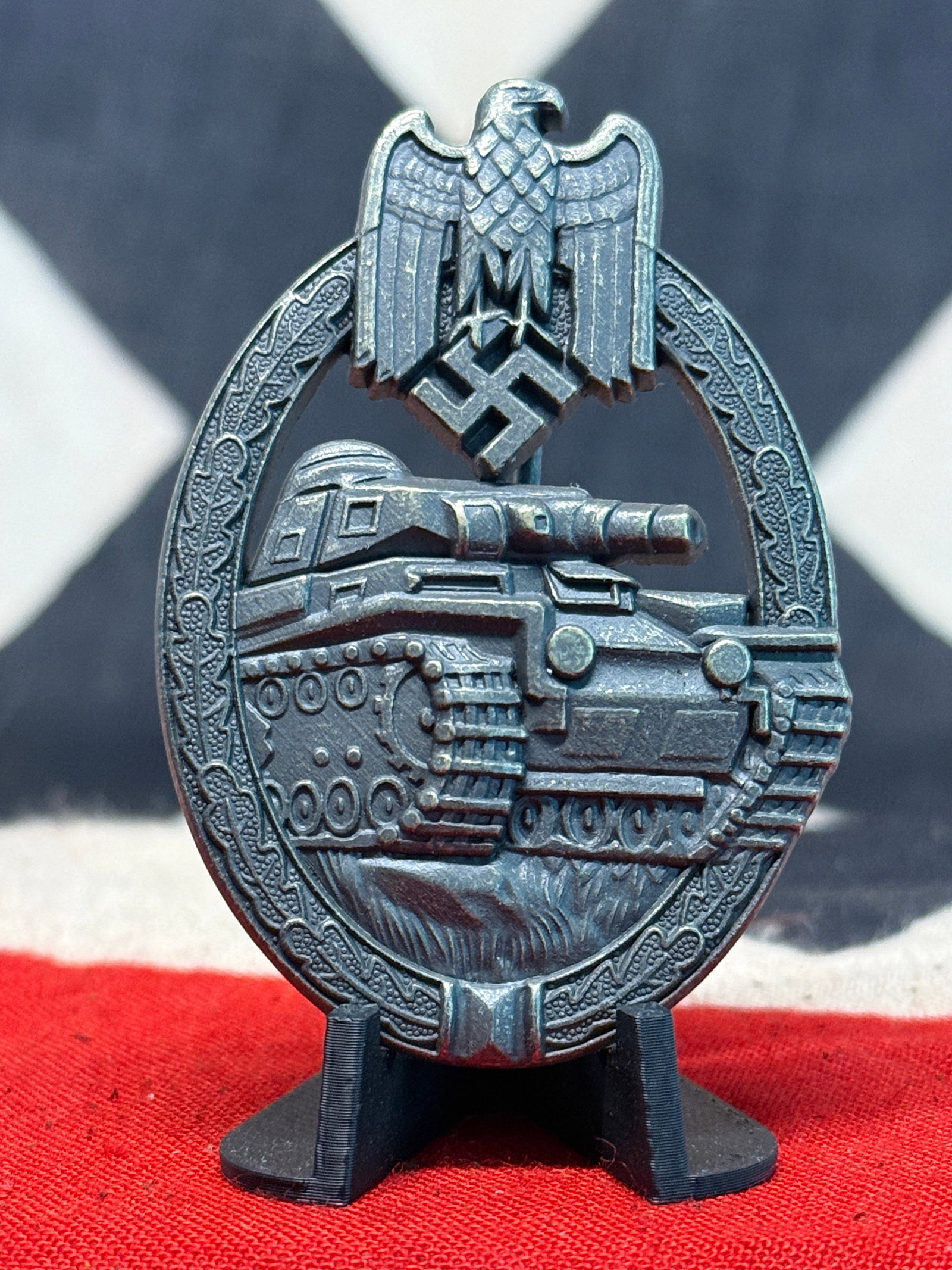 WWII German Panzer Assault Badge in Silver – Armored Combat Decoration: A substantial WWII German Panzer Assault Badge featuring a detailed German tank advancing across a textured battlefield within an oval oak-leaf wreath. At the top is the national eagle with outstretch
