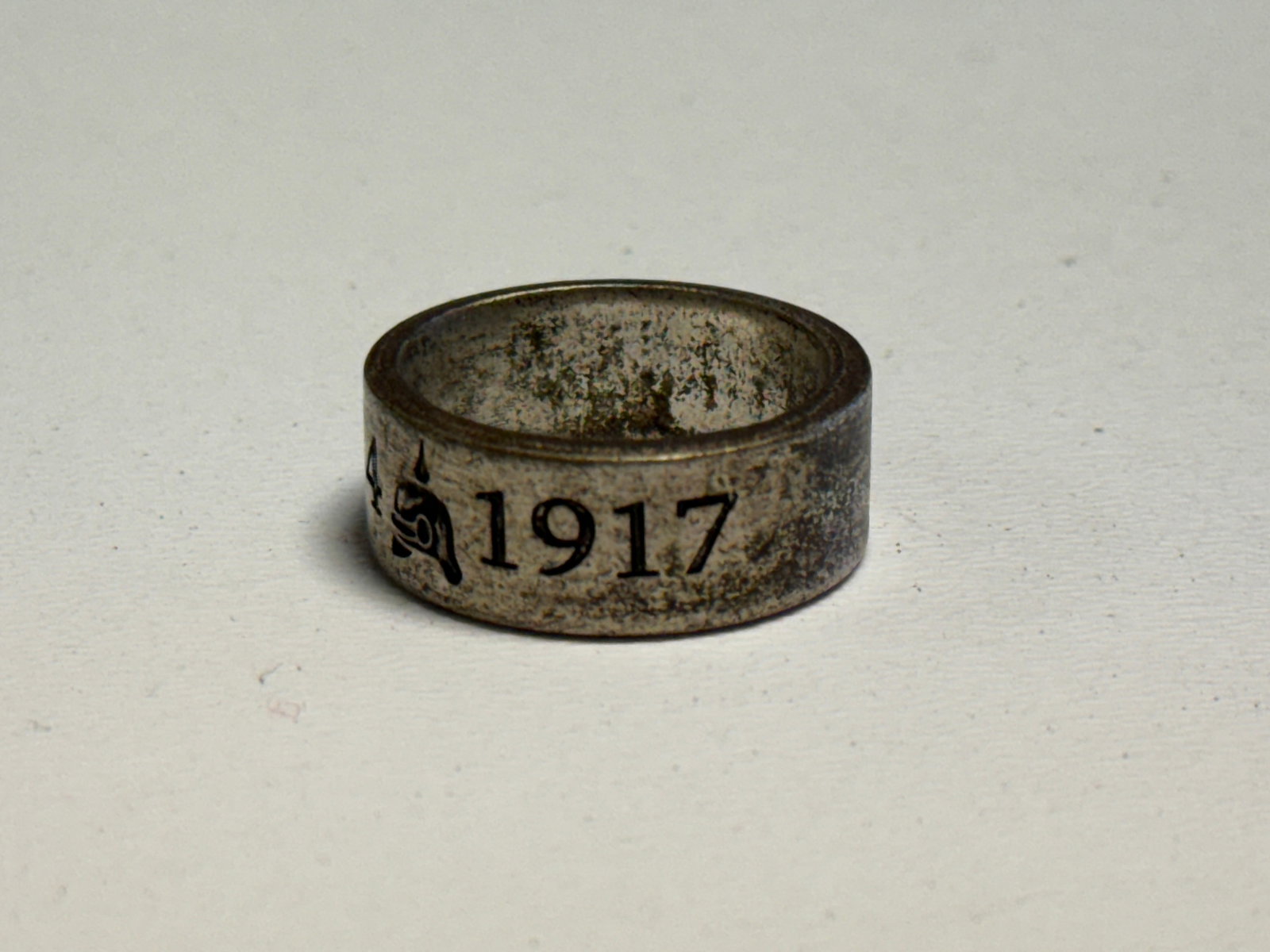 WWI German Imperial 1914–1917 Trench Art Ring with Pickelhaube: WWI German Imperial period metal trench art finger ring featuring engraved dates “1914” and “1917” separated by a detailed Pickelhaube spiked helmet motif. The broad band has a simple 