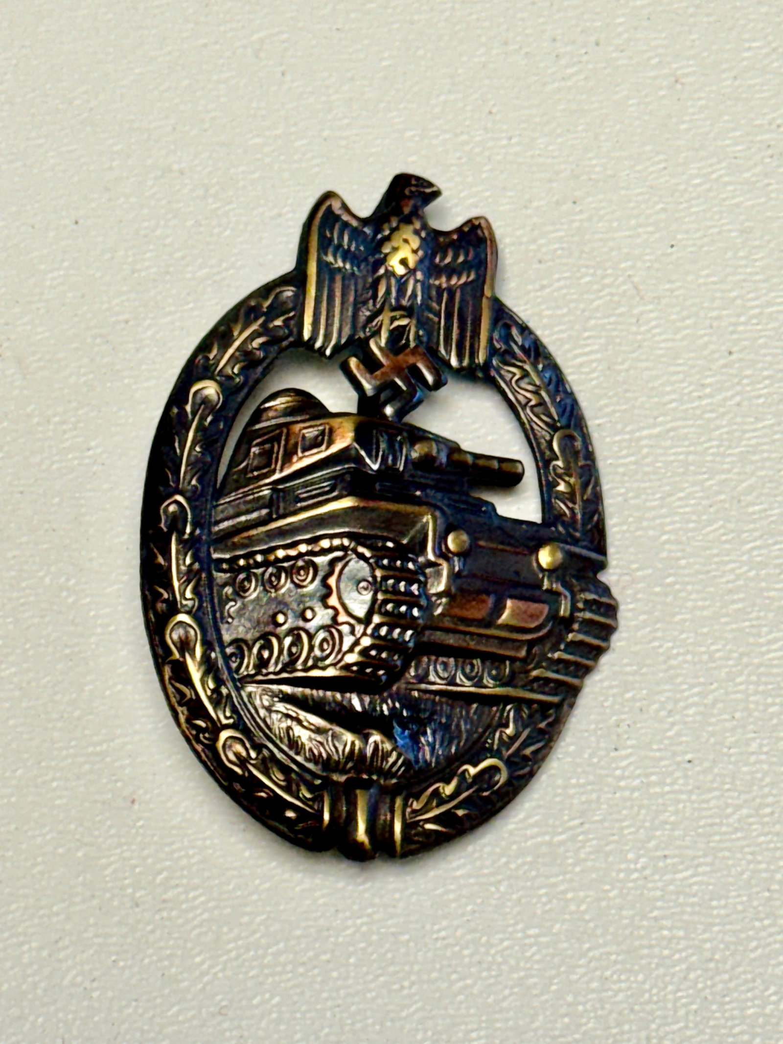 WWII German Panzer Assault Badge – Tank Combat Award with Eagle & Swastika: WWII German Panzer Assault Badge featuring a highly detailed armored tank advancing across a textured battlefield, surrounded by an oval oak-leaf wreath and surmounted by a German national eagle clutc