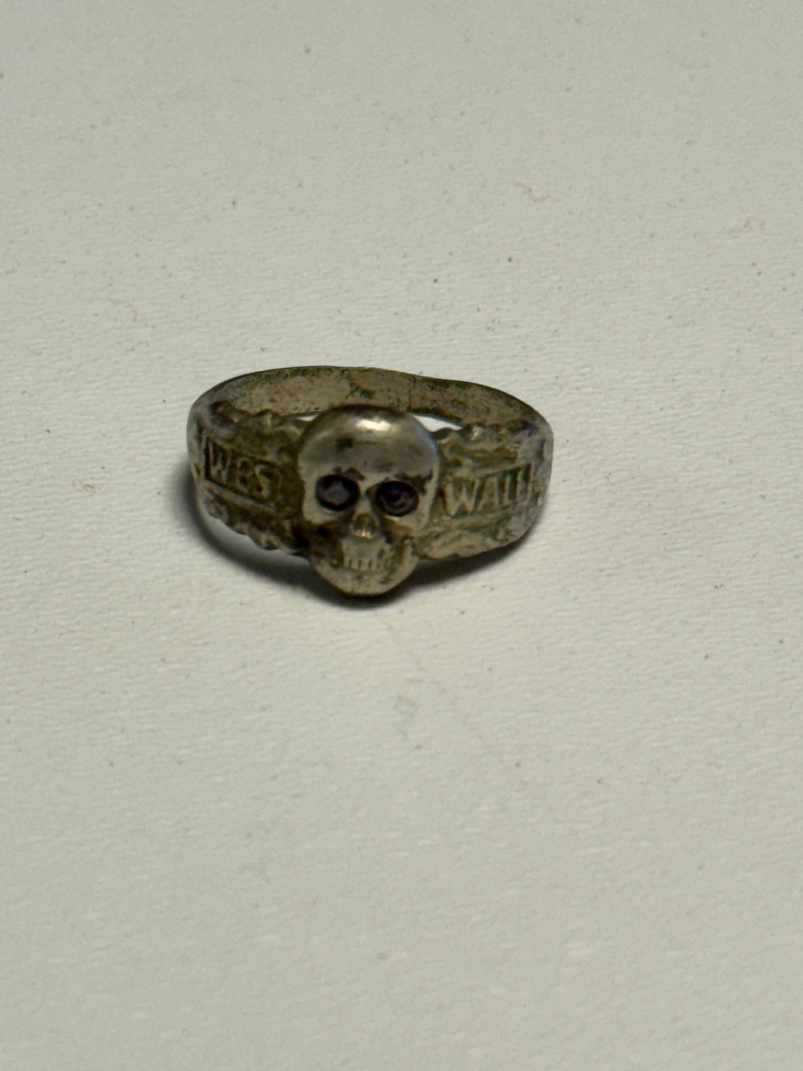 WWII German Waffen-SS “Meine Ehre Heißt Treue?? Totenkopf Skull Ring: WWII German Waffen-SS themed finger ring featuring a prominent raised Totenkopf skull at the center with dark inset eyes and deeply modeled facial details. The shoulders of the band carry raised Gothi