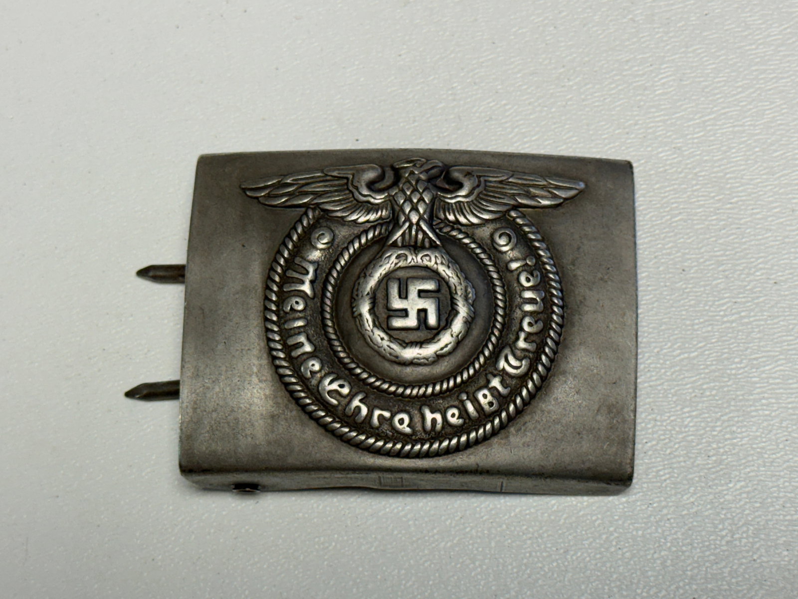WWII German SS “Meine Ehre Heißt Treue?? Enlisted Belt Buckle: WWII German SS enlisted-style belt buckle featuring a prominent raised eagle above a circular rope-bordered design with a central swastika surrounded by an oak-leaf wreath and the SS motto “Meine Eh