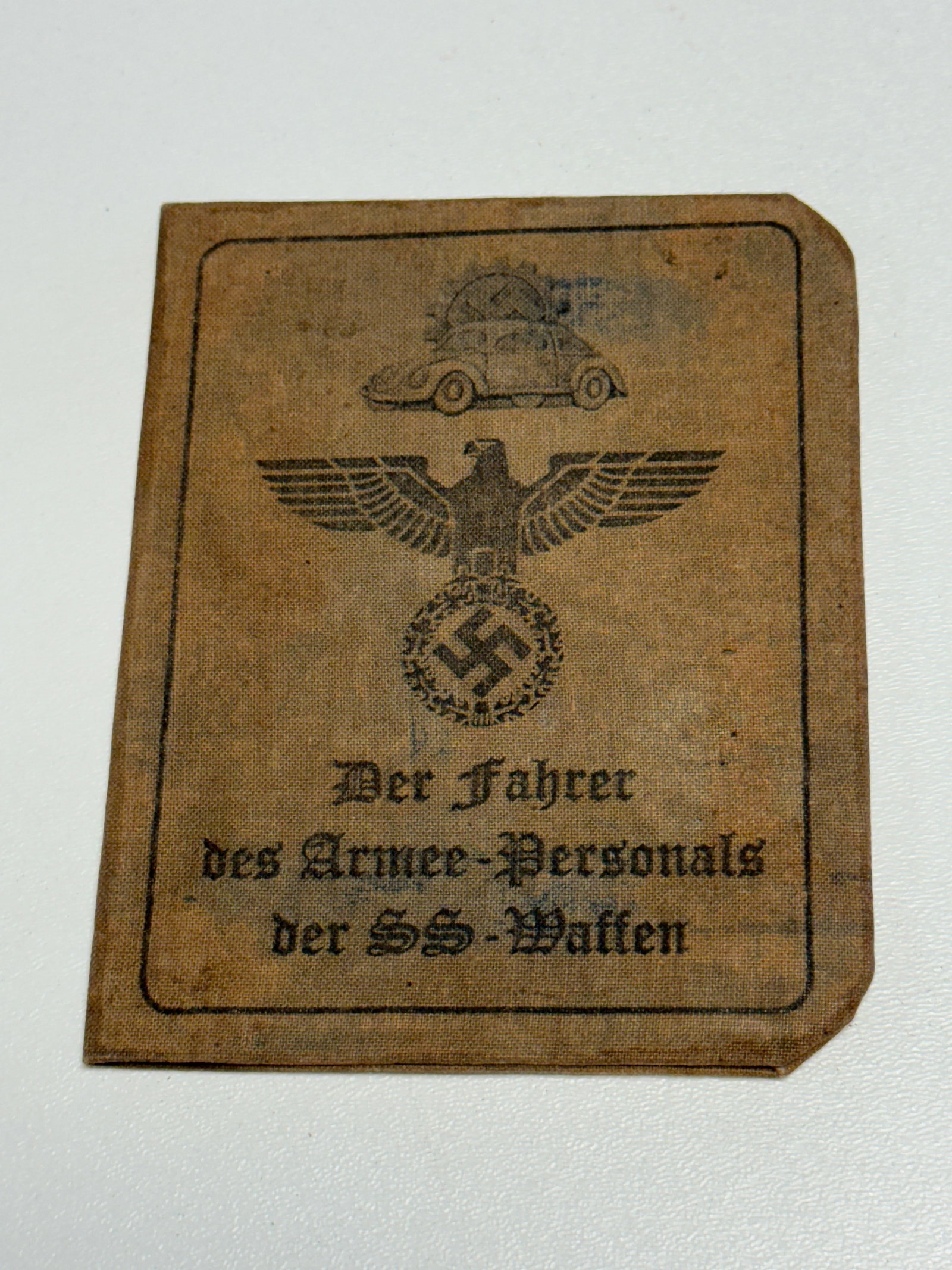 WWII German Waffen-SS Armed Forces Personnel Driver Identification & Travel Pass: WWII German Waffen-SS identification and travel document issued for a driver associated with Waffen-SS armed forces personnel, housed within a brown cloth-covered folding booklet. The cover displays a