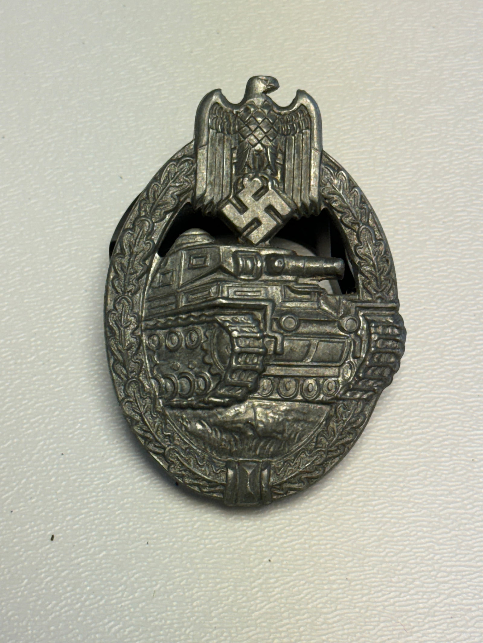 WWII German Panzer Assault Badge in Silver – 1942 AWS Marked: WWII German Panzer Assault Badge featuring the distinctive oval oak-leaf wreath surrounding a detailed armored tank advancing across the ground, surmounted by a German national eagle and swastika. The