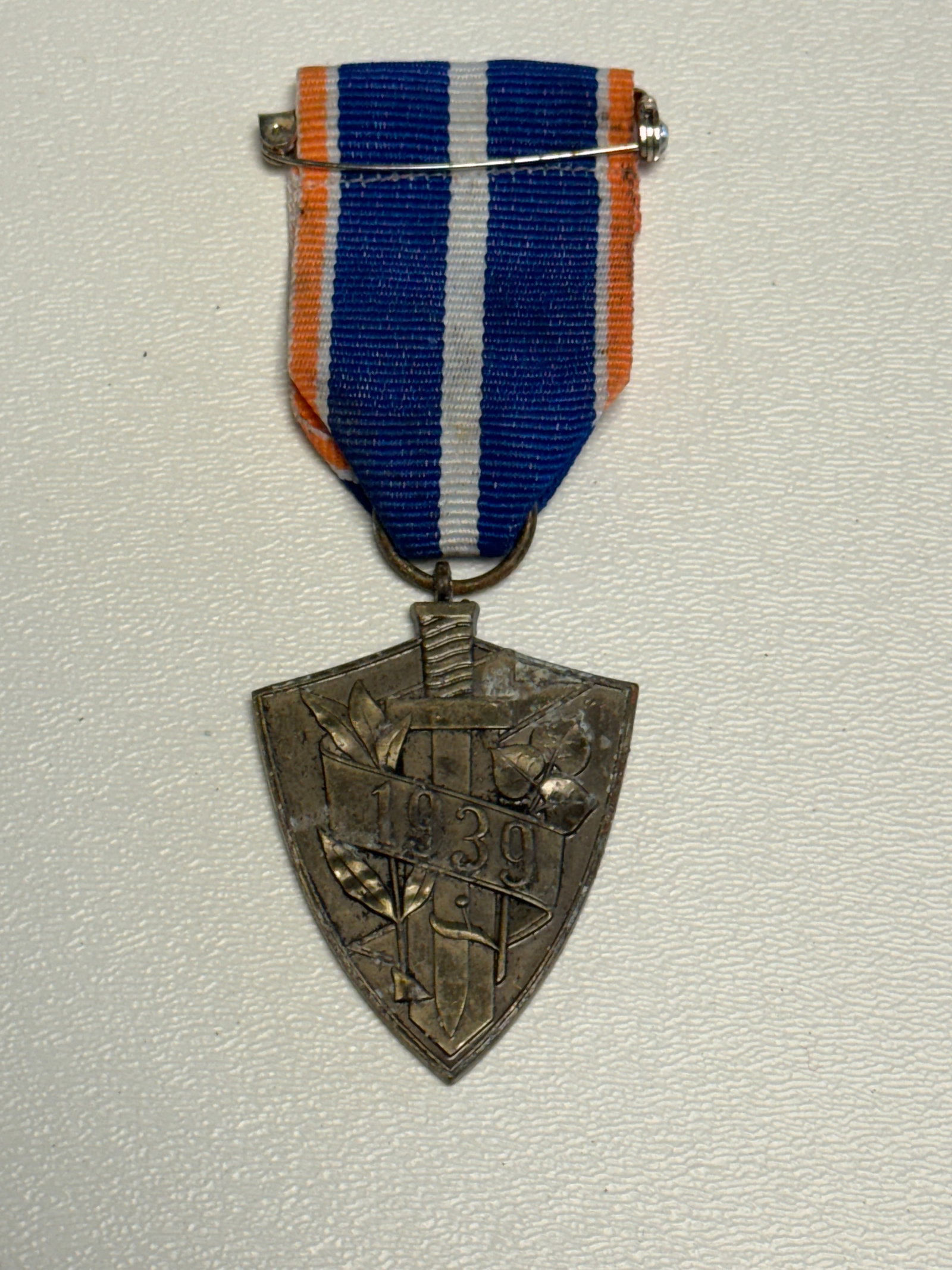 1939 Slovak Military Defense Medal – Javorina Orava Campaign Award: Distinctive 1939 Slovak military commemorative medal featuring a shield-shaped pendant suspended from a blue, white and orange striped ribbon with horizontal pin attachment. The obverse displays the p