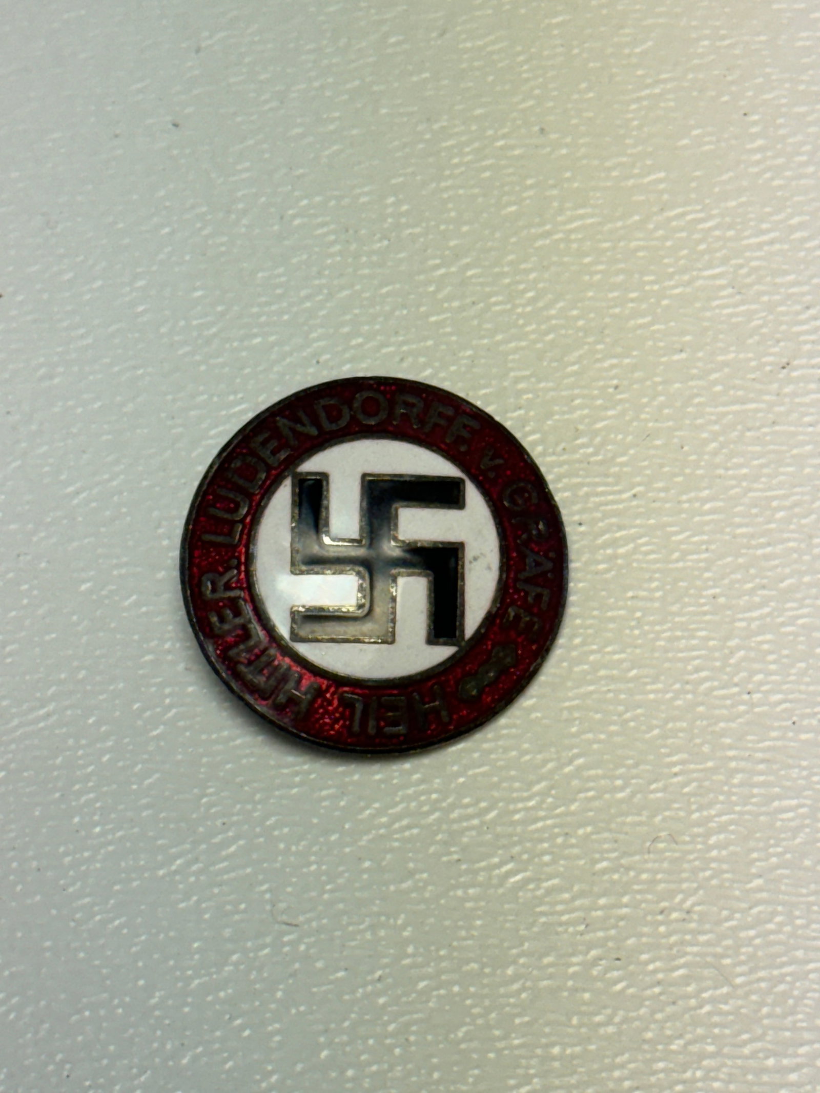WWII German NSDAP Party Membership Badge – RZM M1/73 Marked: WWII German National Socialist German Workers’ Party (NSDAP) membership badge featuring a circular red enamel outer border inscribed “NATIONAL-SOZIALISTISCHE D.A.P.” surrounding a white enam