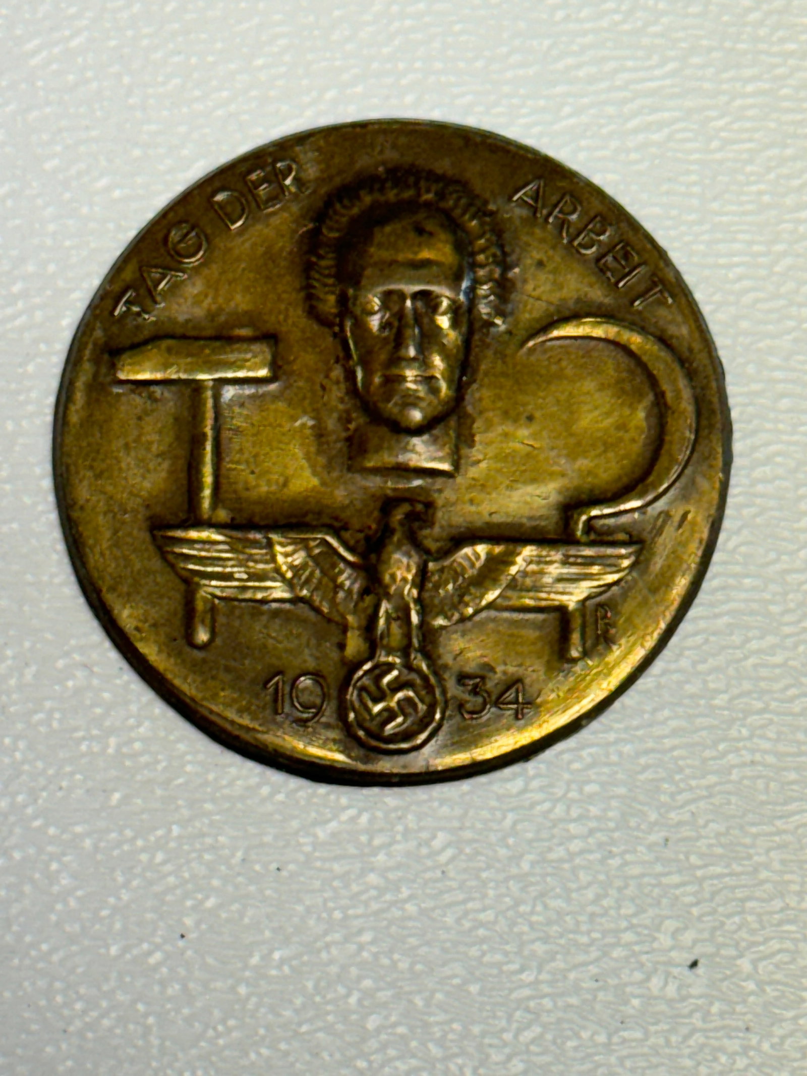 WWII German 1934 “Tag der Arbeit?? Labor Day Commemorative Tinnie Badge: WWII-era German commemorative tinnie dated 1934 and inscribed “TAG DER ARBEIT,” translating to “Day of Labor,” associated with the German May Day labor celebrations of the period. The 
