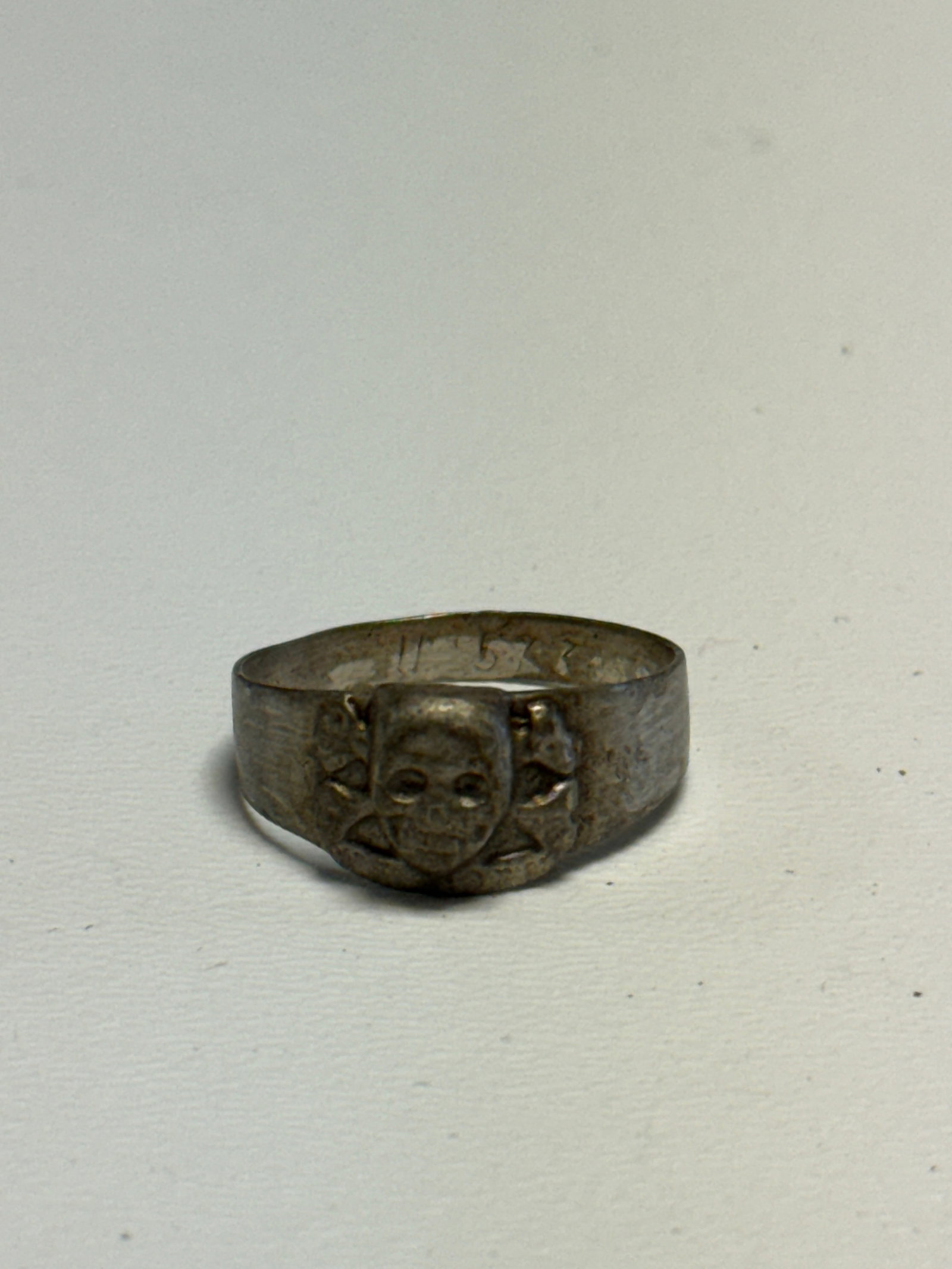 WWII German Waffen SS Totenkopf Skull & Crossbones Ring – D.R.G.M. Marked: WWII German ring featuring a prominent raised Totenkopf skull and crossbones motif across the face, a design closely associated with German military and SS symbolism of the period. The broad metal ban