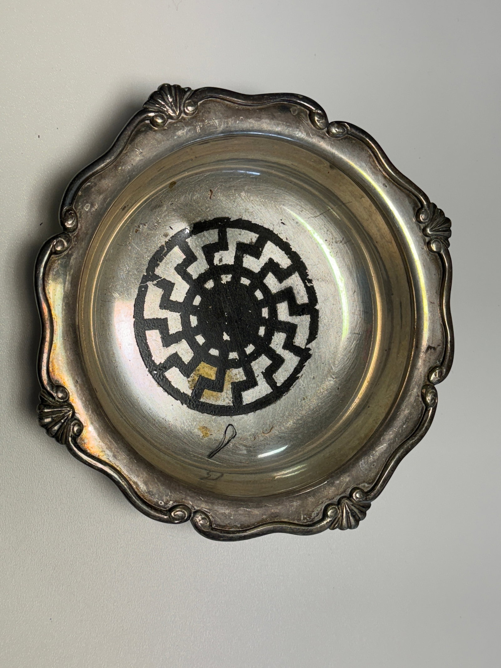 WWII German Black Sun Sonnenrad Silver-Tone Presentation Dish: WWII German silver-tone presentation or commemorative dish featuring a prominent black circular Sonnenrad or “Black Sun” motif applied to the center, composed of twelve radial sig-like element