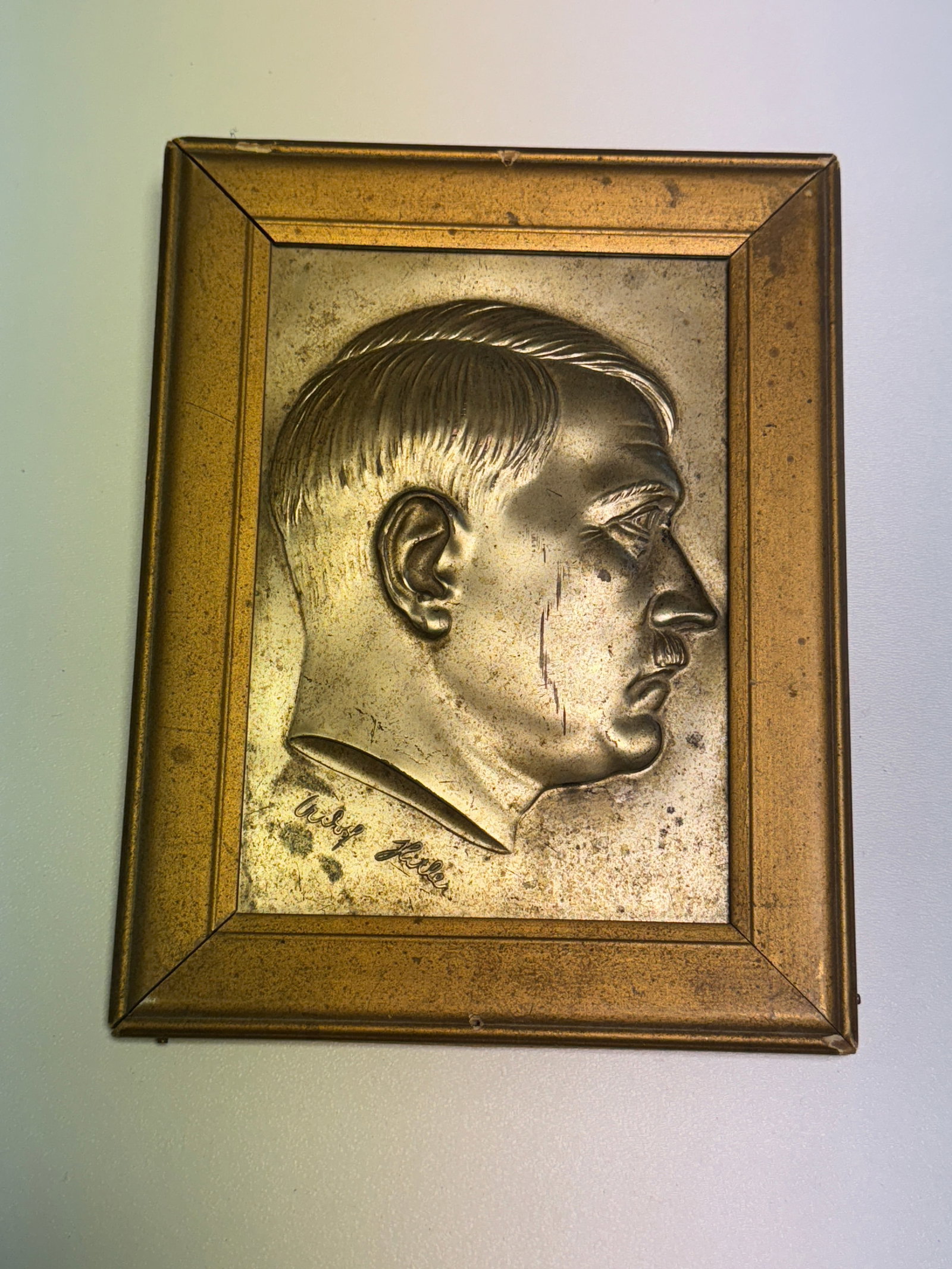 WWII German Adolf Hitler Raised Relief Portrait Plaque in Period Frame: WWII-era German decorative portrait plaque featuring a large raised right-facing profile of Adolf Hitler presented within a rectangular metallic-finish frame. The portrait is executed in pronounced re