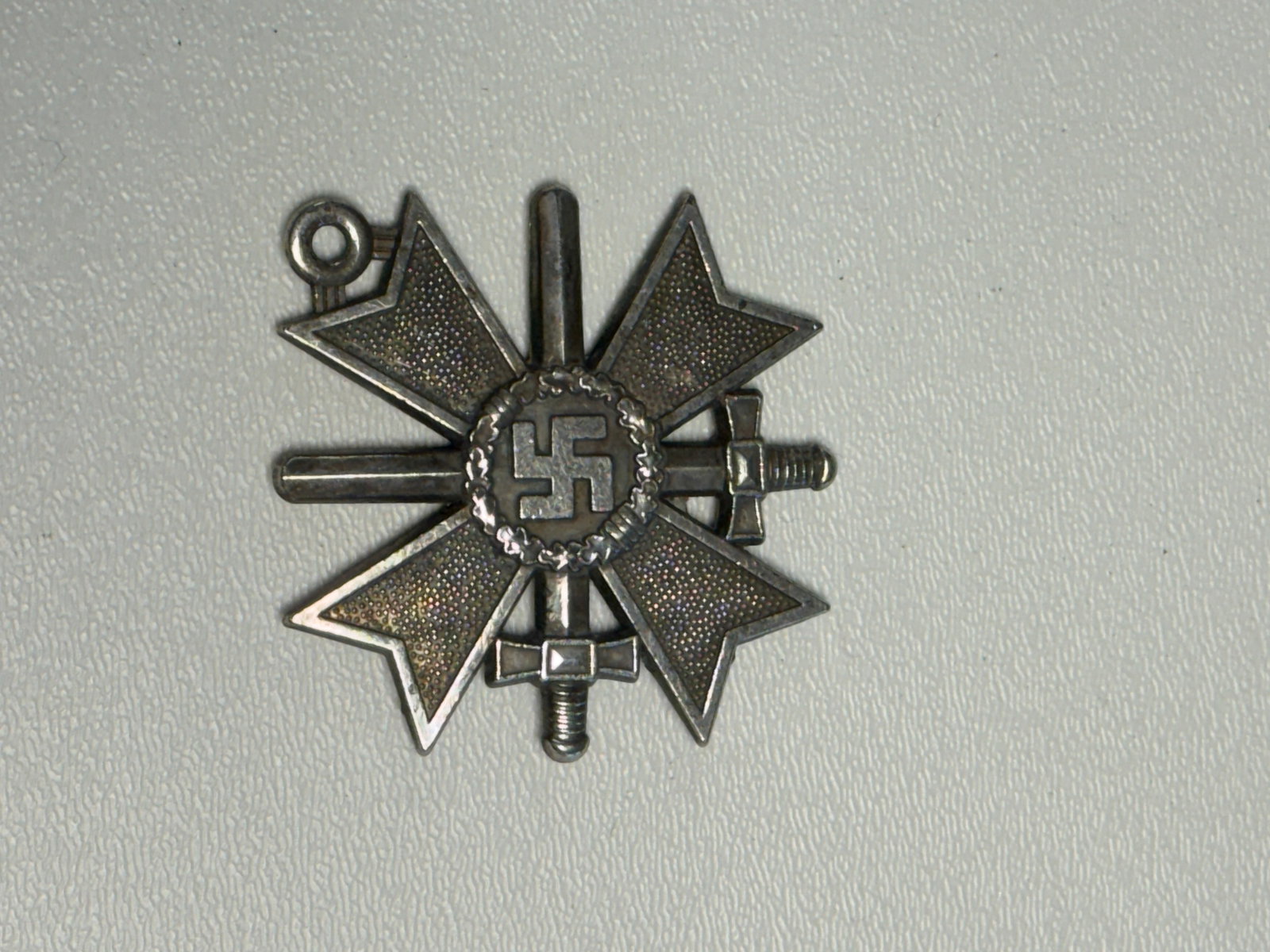 WWII German 1939 War Merit Cross with Swords Medal: WWII German 1939 War Merit Cross with Swords featuring a four-armed cross with finely stippled fields, raised borders, crossed swords positioned between the arms, and a central circular medallion surr