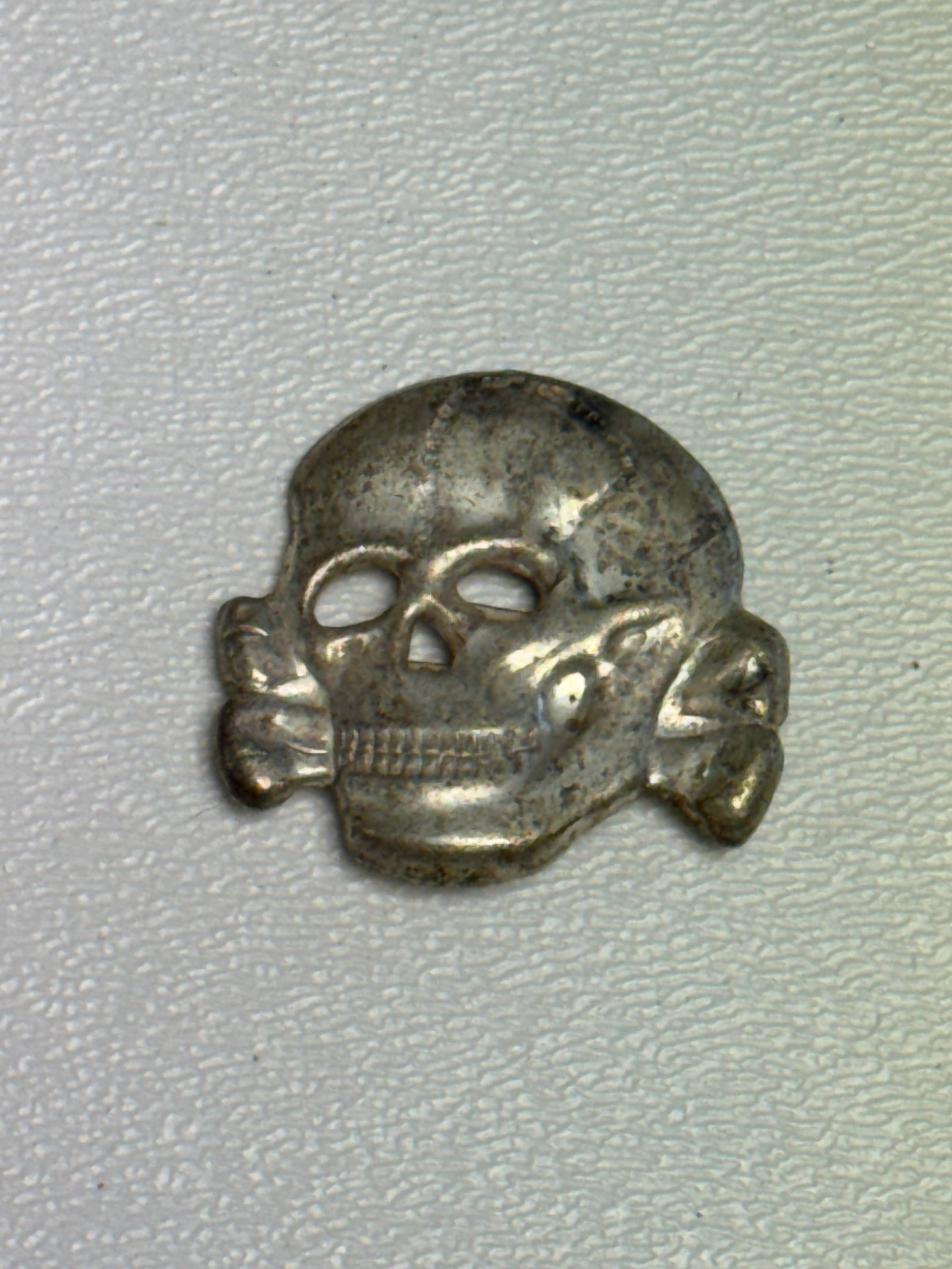 WWII German Waffen-SS Totenkopf Skull & Crossbones Cap Insignia: WWII German Waffen-SS Totenkopf skull and crossbones insignia featuring the distinctive frontal skull with pronounced eye and nasal openings, detailed teeth, and crossed bones extending to either side