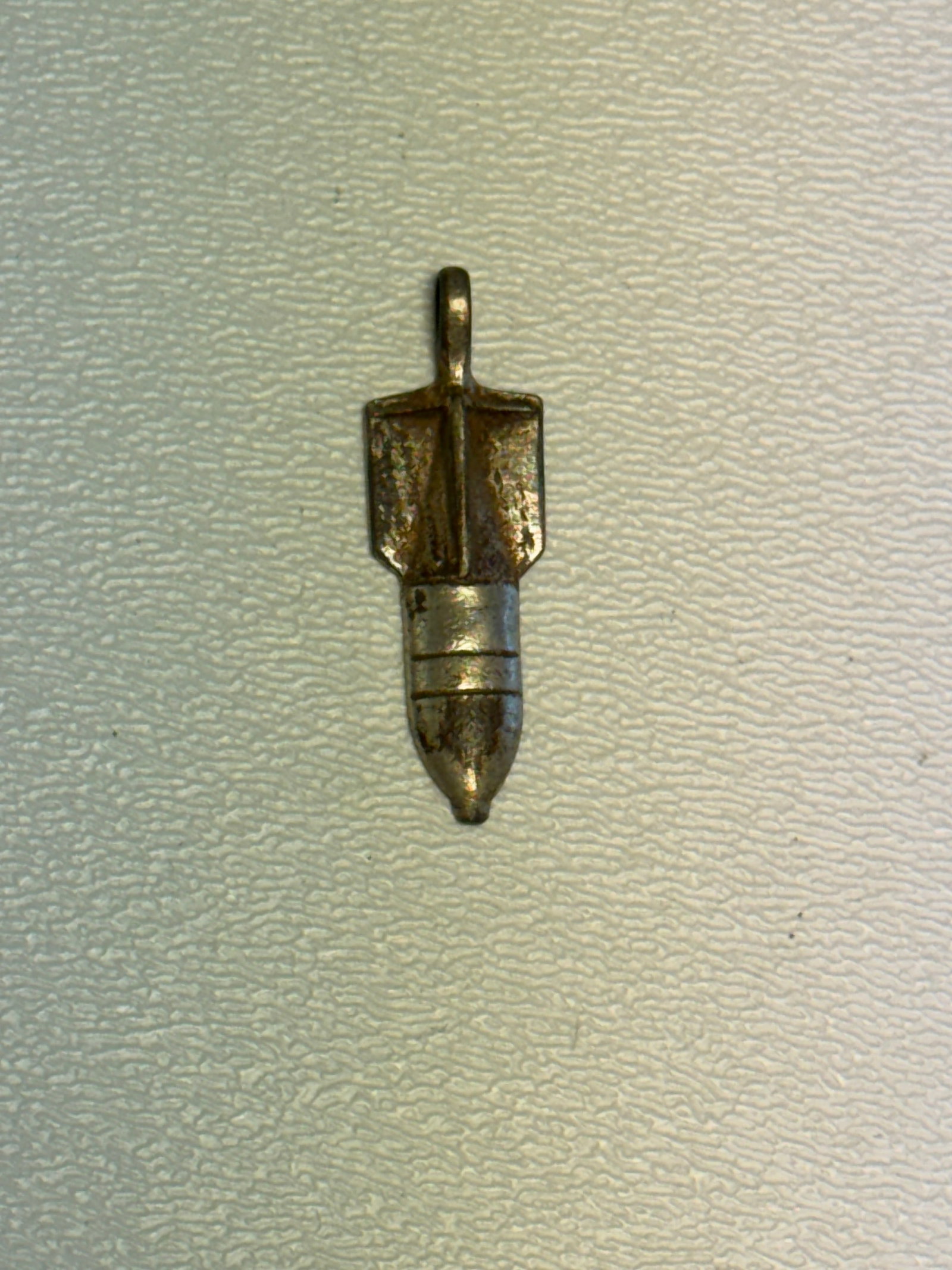 WWII German Deutsches Reich Gebrauchs Musterschutz Miniature Bomb Charm: Unusual WWII-era German miniature bomb-form metal charm or pendant featuring a pointed bomb body with raised horizontal bands, pronounced tail fins, and an integral suspension loop at the top. The rev