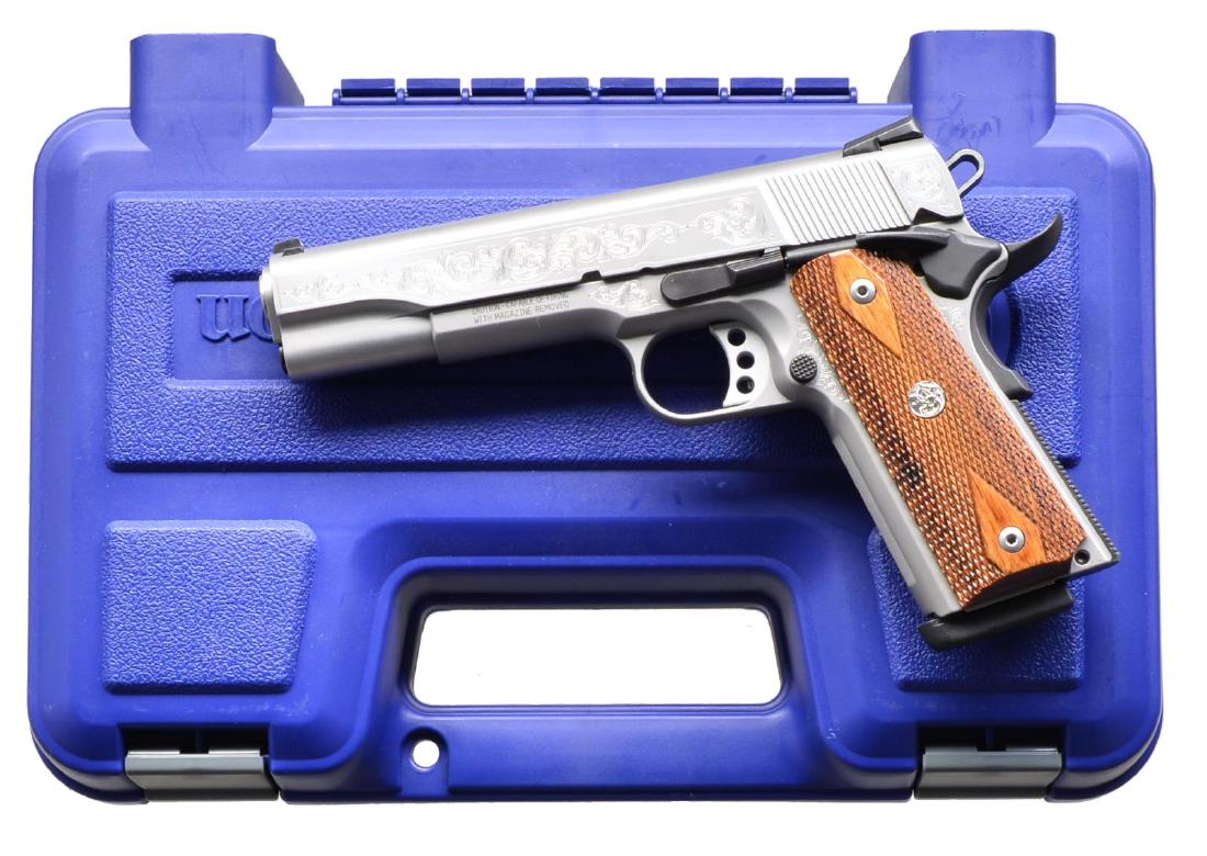 SMITH & WESSON 1911 100TH ANNIVERSARY PISTOL.: Cal. 45 ACP. S# JBP0341. Bbl: 5". 3 Dot dovetailed sights. Stainless steel frame, slide & bbl. Checkered walnut grip panels w/ escutcheon diamonds and S&W logo. Slide bears the banner "1911, 100th Ann