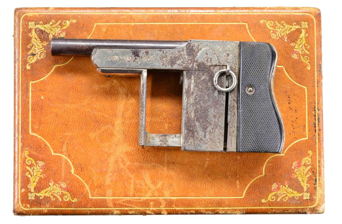 BELGIAN SQUEEZE OPERATED PALM PISTOL.: Cal. 32 Protector. S# 9134. Bbl. 3 1/4" rnd. w/ brass bead sight & rifled bore. Nickel finished action w/ integral box mag. Foliate scroll engraving. Squeeze lever & checkered backstrap have checkered