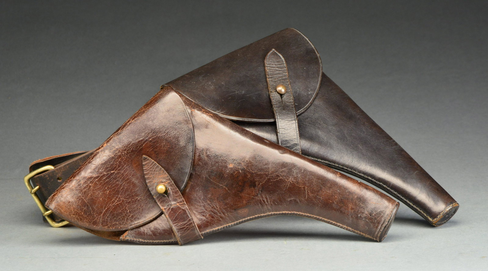 2 WEBLEY REVOLVER HOLSTERS.: 1) MARK VI HOLSTER W/ BELT. Black leather construction w/ brass hardware. Michael Brennan is inked on the inside flap. CONDITION: overall very good w/ only minor scuffing & handling marks. 2) WG ARMY 
