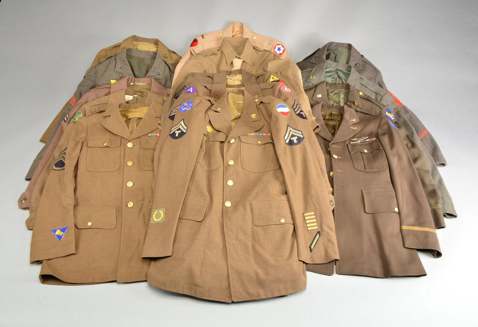 LARGE GROUP OF MOSTLY WWII UNIFORMS.: This lot of 22 uniforms includes a Navy nurse's uniform w/ a Army Service patch on the left shoulder for a 2nd Lt. w/ skirt. / Ike jacket for a private in the Medical Corps w/ 3rd Army patch on left s