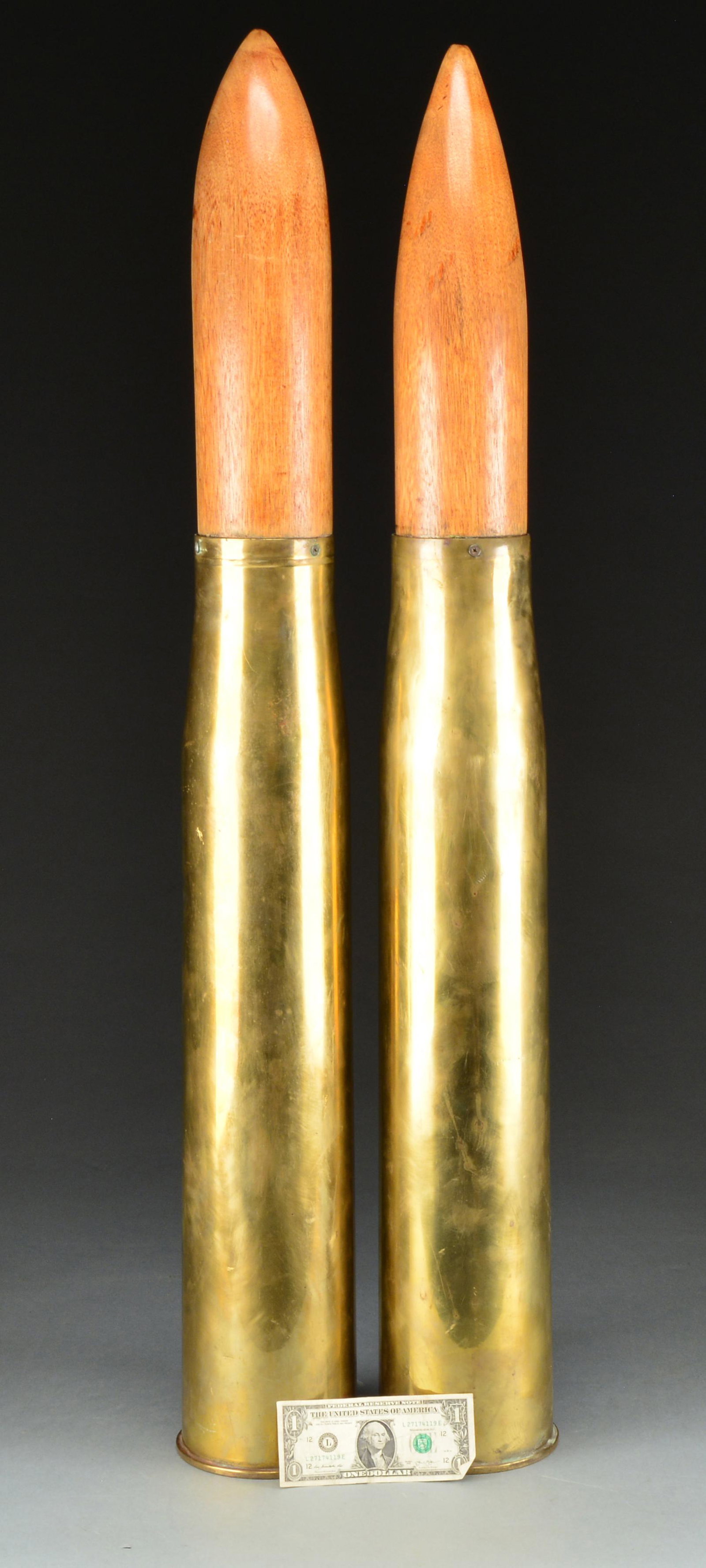 2 LG. INERT ARTILLERY SHELLS.: 2 U.S. 105 mm. brass shells for Mark 16 & 21 guns, both dated 1958. Have hand turned, natural colored, hard wood replica projectiles retained by screws. Approx. 44" long over all, 6" diameter at base.