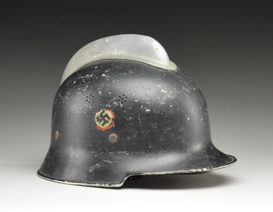 GERMAN FIREMAN'S HELMET WITH COMB.: Model 34 helmet stamped on inside "BXE / VORSCHRIFTSMASS / LT GETESZ 3.5.34". Black painted helmet w/ alloy comb & Party symbol decal on right side. Each side has two groups of 8 hole vents. Leather l
