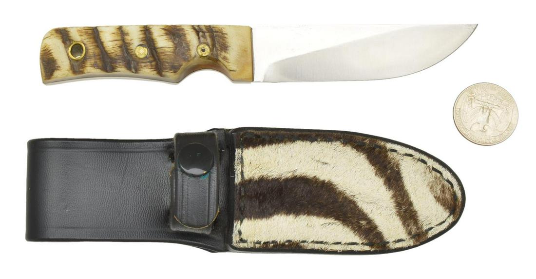 CUSTOM MADE KNIFE FROM RANDALL MADE TRIATHLETE: RANDALL MADE TRIATHLETE BOOT KNIFE. Consignor states Tom Clinton Safari special. Overall: 6 1/2". Stainless steel 3" blade w/ thumb notches. Knife has been altered to conform to fossil walrus scales w