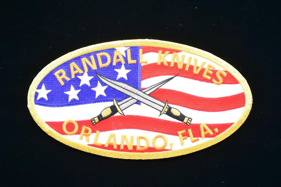 RANDALL KNIVES PATCH.: 10" Length oval patch for Randall Knives w/ the American flag in the background & gold colored trim. CONDITION: near excellent. (02-17362/MD). $150-250.