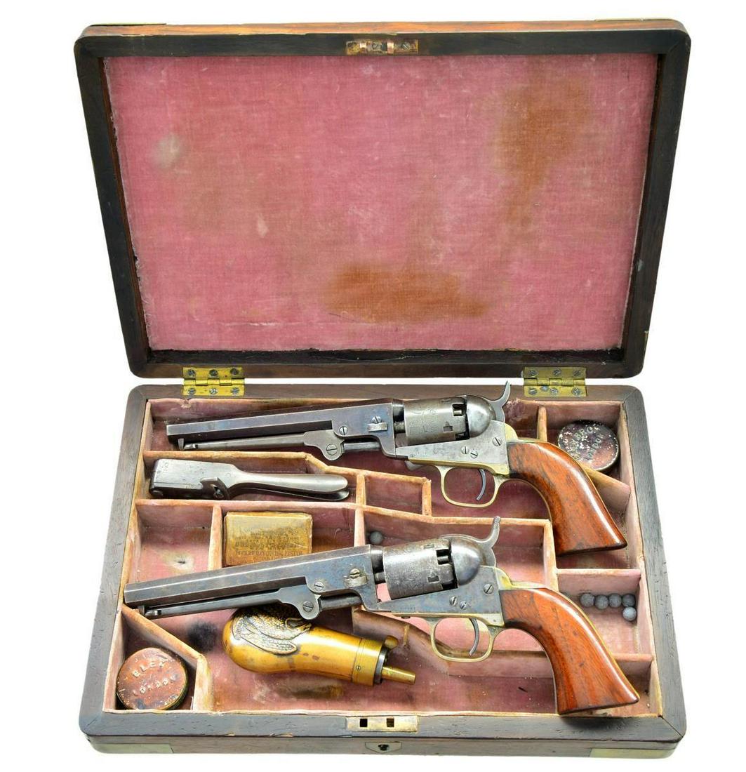 PAIR CASED COLT 1849 POCKET MODEL REVOLVERS.: Both: Cals. 31. Bbls. 6” octagon w/ Hartford addresses & brass cone front sights. Round five shot cyls. w/ stagecoach scene roll engravings. Blue & case colored finishes w/ nickel finish brass b