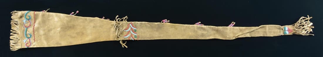 NATIVE AMERICAN BEAD DECORATED RIFLE SHEATH.: 47" x 6.5" leather sleeve with beaded design at mouth, middle, & tip in green, blue, and browns, larger clear faceted beads on tassels. Should fit a long barrel Winchester model 1873 rifle. CONDITION: