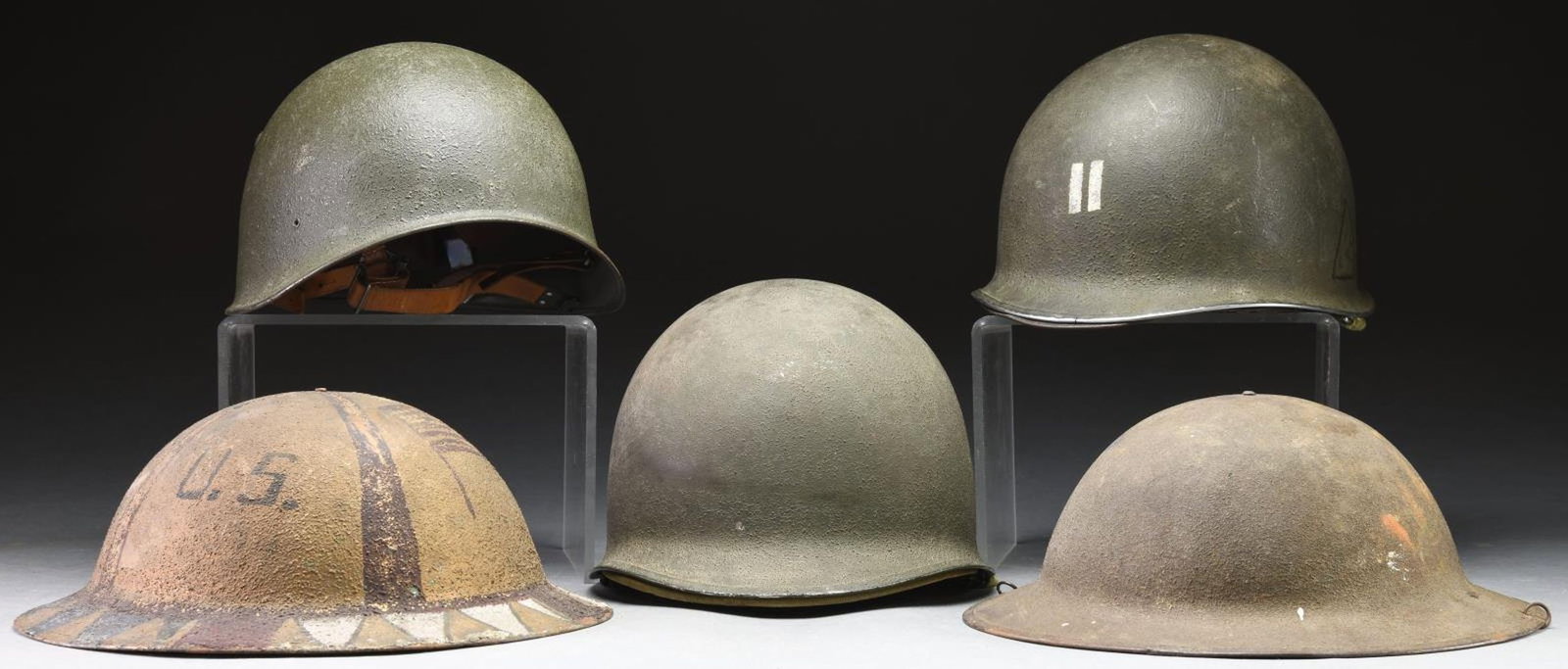 4 US HELMETS, 1 FRENCH HELMET, & A EUROPEAN HELMET: 1) WWII US. This front seam, fixed bale WWII M1 helmet has a sanded field green finish and is equipped with a rare Hawley liner. The liner is stenciled on the rear strap "BIECHLIN, E. R. 94299587". Th