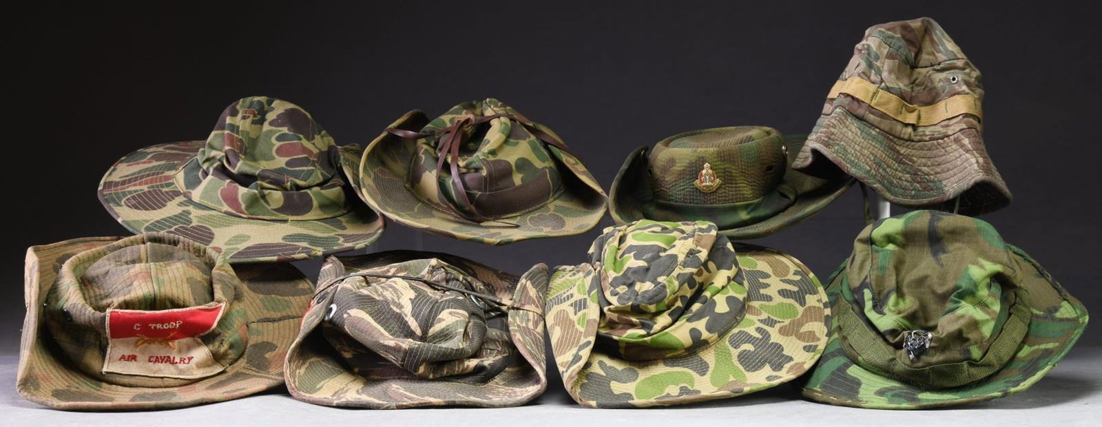 GROUP OF 6 BUSH HATS & 2 BOONIE HATS.: Group of 6 bush hats and 2 boonie hats of varying camouflage patterns. One hat with a "READY RELIABLE EXACT", one with an embroidered flag that reads "C TROOP/ (CROSSED SWORDS)/ AIR CAVALRY", and 1 wi