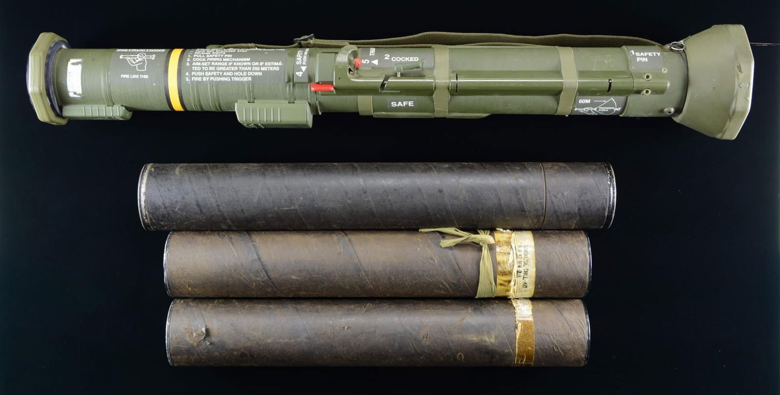 INERT AT-4 LAUNCHER & TRAINING SHELL TUBES.: 1) Inert AT-4 launcher tube. Tube retains instruction markings and canvas web sling. CONDITION: good overall, exhibiting some mild marks from storage and handling. 2) 75mm M38A1 / M48 Inert cardboard