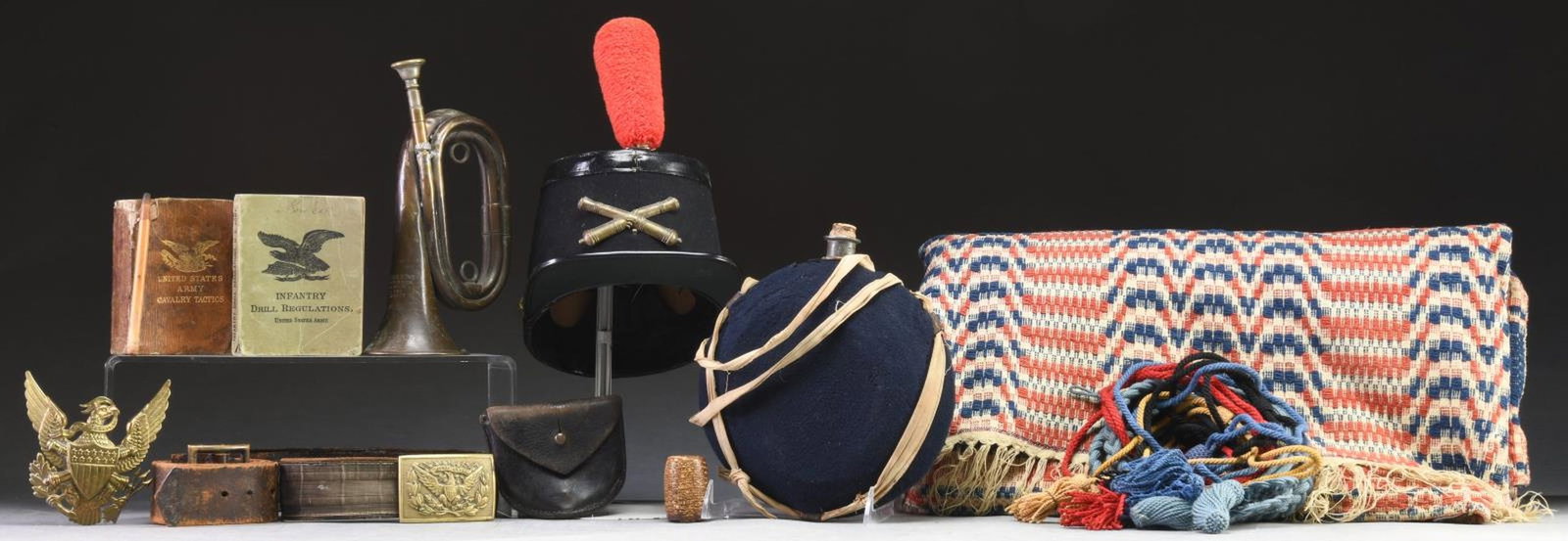 CIVIL WAR & INDIAN WAR ACCOUTREMENTS & RELATED: MATERIAL. This lot consists of 1 blue covered, bullseye canteen with severe dents. / 1 Red, white, & blue Civil War era coverlet. / 1 Cap eagle for an M1881 spike helmet. / 1 Well-worn Indian War offi