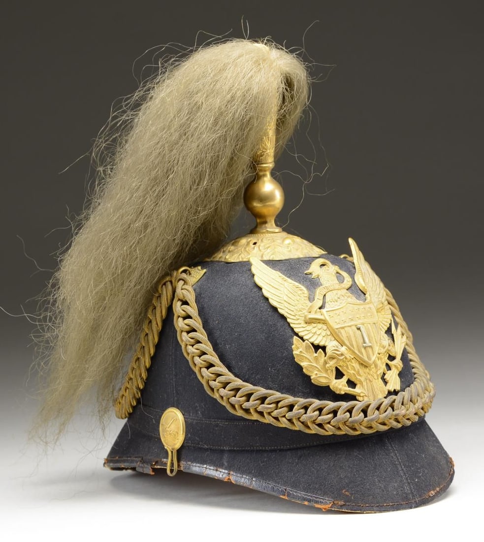 US M1881 OFFICER’S PLUMED HELMET FOR THE 1st US: CAVALRY. Helmet has a gilded brass plume holder w/ a white or very faded yellow plume atop an oak leaf base. The front plate is a gilded brass eagle w/ an applied shield & crossed sabers on the front.