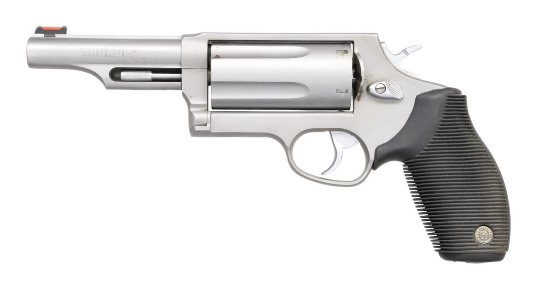 TAURUS JUDGE DA REVOLVER.: Cal. 45 Colt/410. S# GN754390. Bbl. 4" with rib and shrouded ejector. Orange fiber optic front sight. Five-shot fluted cyl. Stainless construction. Rubber grips. CONDITION: stainless finish shows smal