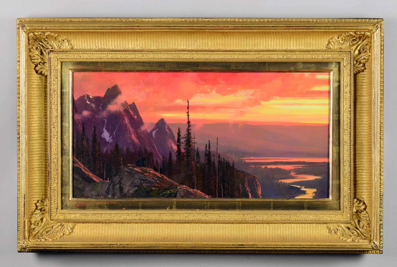 MICHAEL COLEMAN (American, b 1946) SUNSET IN THE: NORTHERN ROCKIES. Oil on board depicts a brilliant sunset with colorful clouds setting the tone. Rugged mountain tops with traces of snow, pine trees in the foreground, a family of bears on a rocky ou