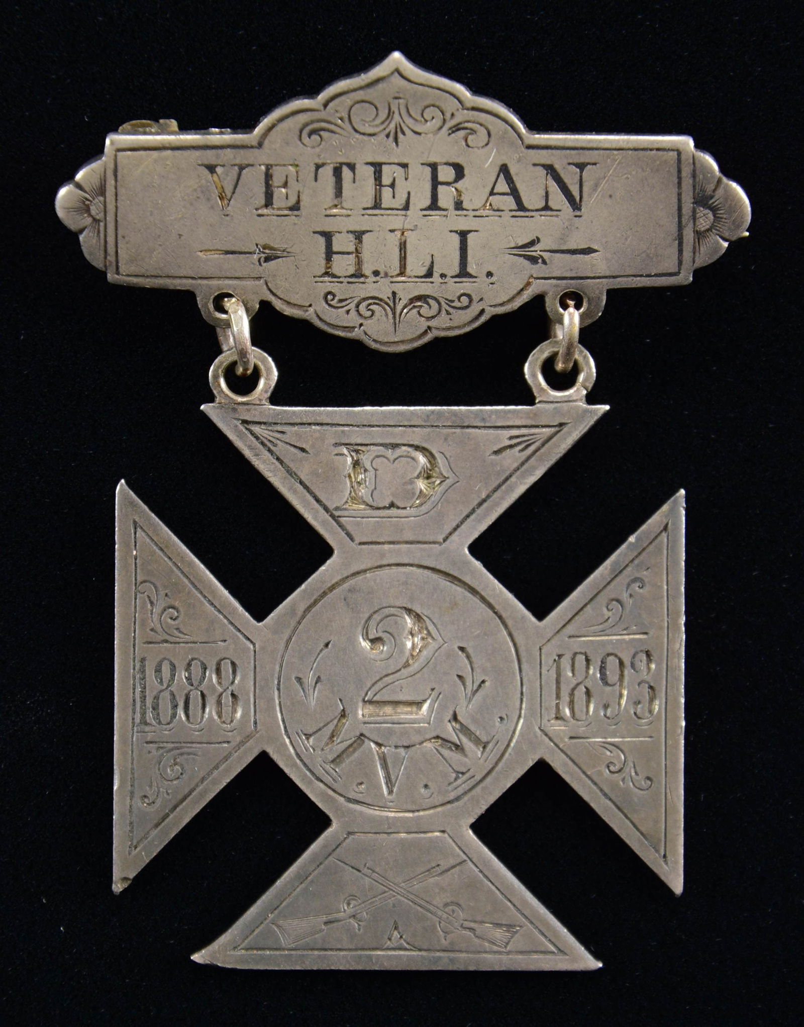 SILVER MASSACHUSETTS VOLUNTEER MILITIA BADGE.: This badge measures 2 3/4" x 1 1/2". The top bar is engraved "VETERAN H.L.I.", and the drop is engraved "D 2 N.V.M. (crossed rifles) 1888 1893". The reverse of the drop is professionally hand-engraved