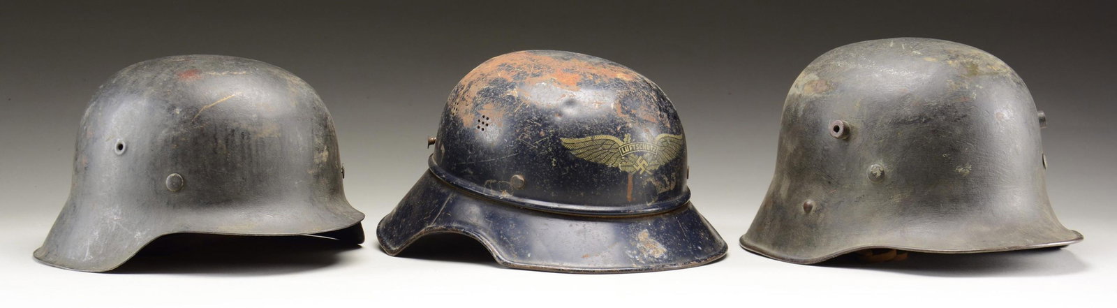 3 GERMAN HELMETS.: 1) A fine example of an Austrian M1916 helmet reissued to WWII German forces. The helmet has a dark gray/green painted finish with a single Wehrmacht decal on the left side. The interior left of the h